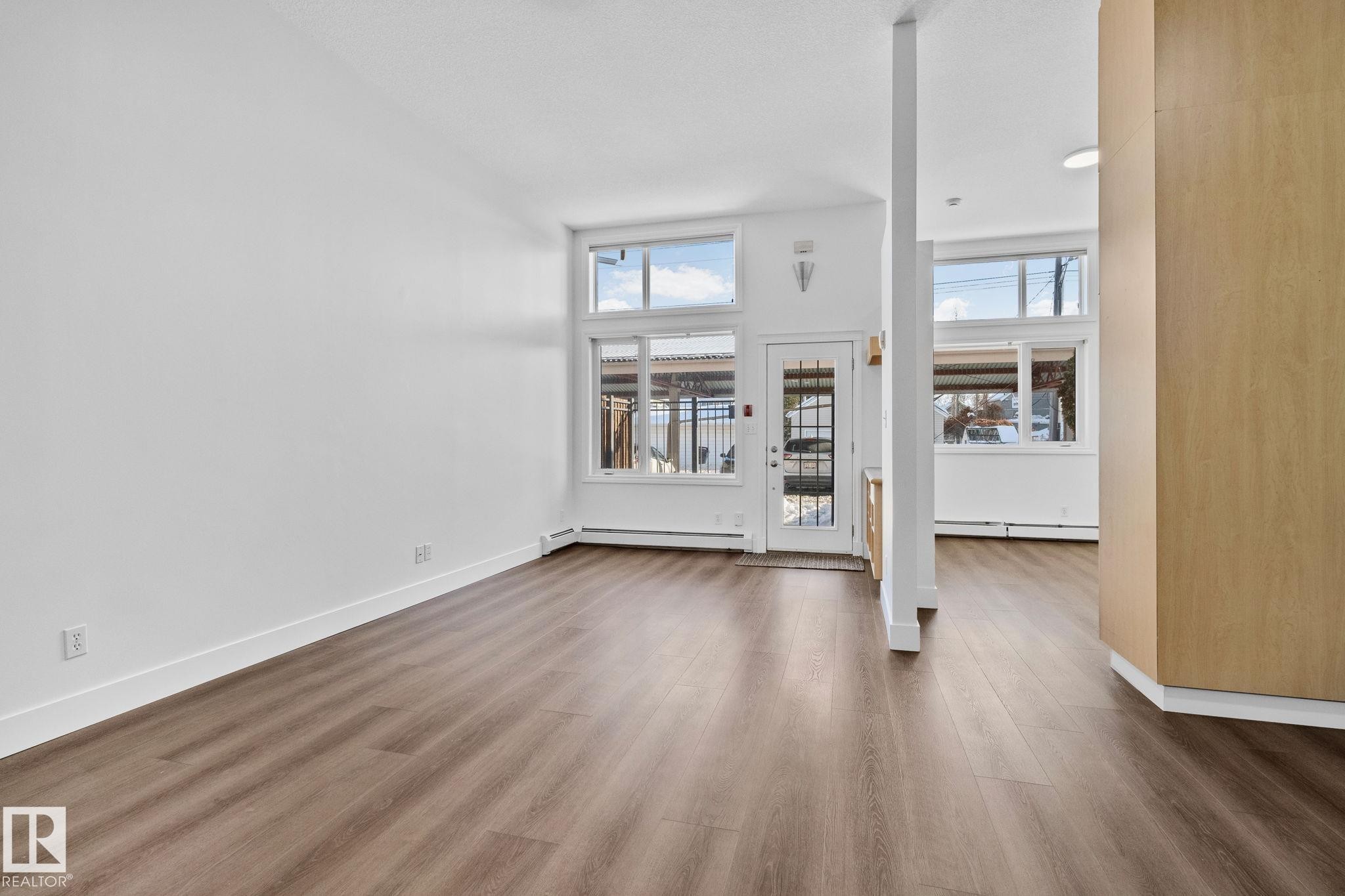 This expansive room features wide plank flooring and white walls, creating a bright and airy atmosphere - 116 11033 127 Street, Edmonton, AB - Indoor Photo Showing Other Room