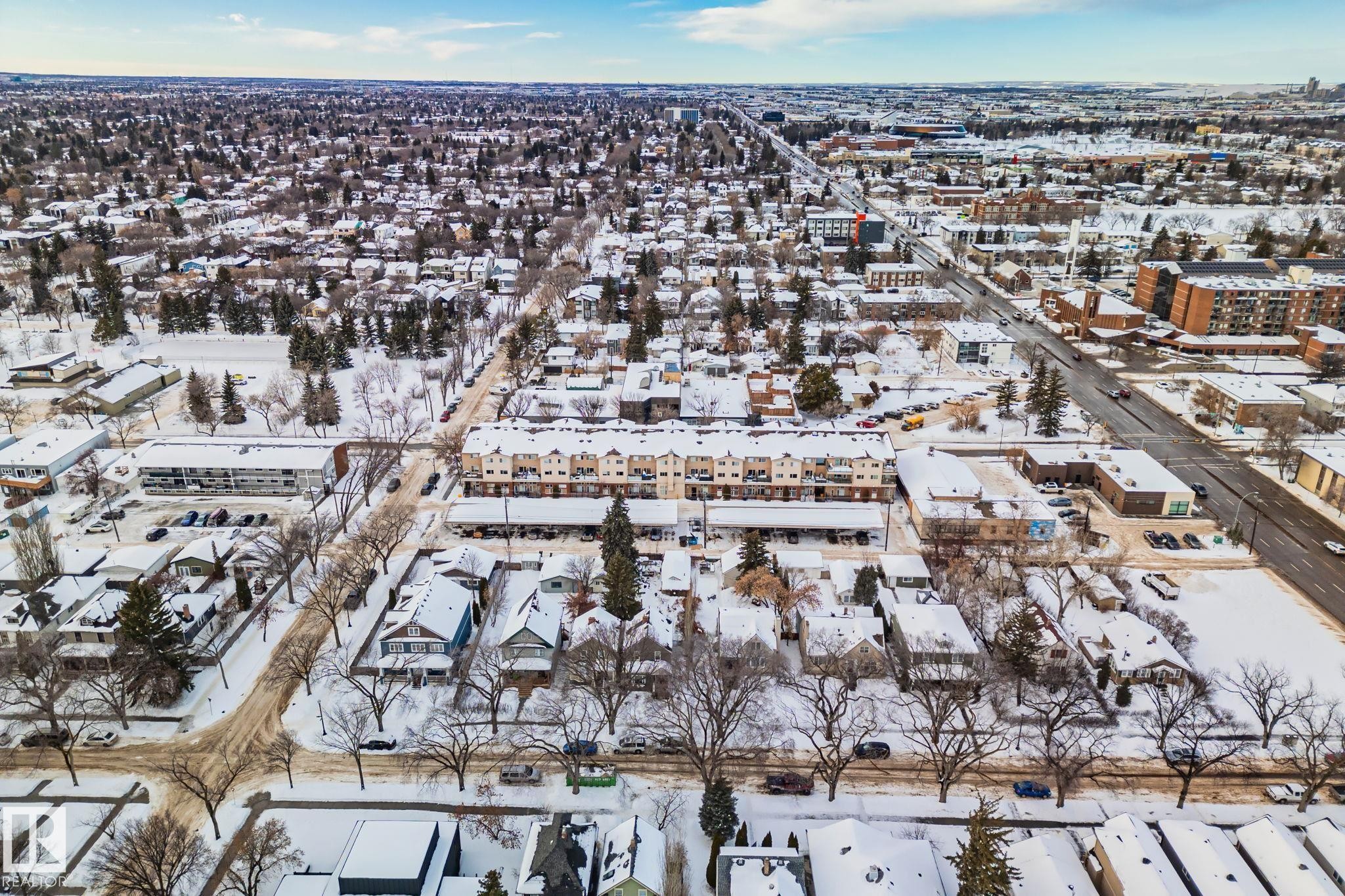 An aerial view showcasing a neighborhood with residential properties and commercial buildings, all covered in snow - 116 11033 127 Street, Edmonton, AB - Outdoor With View