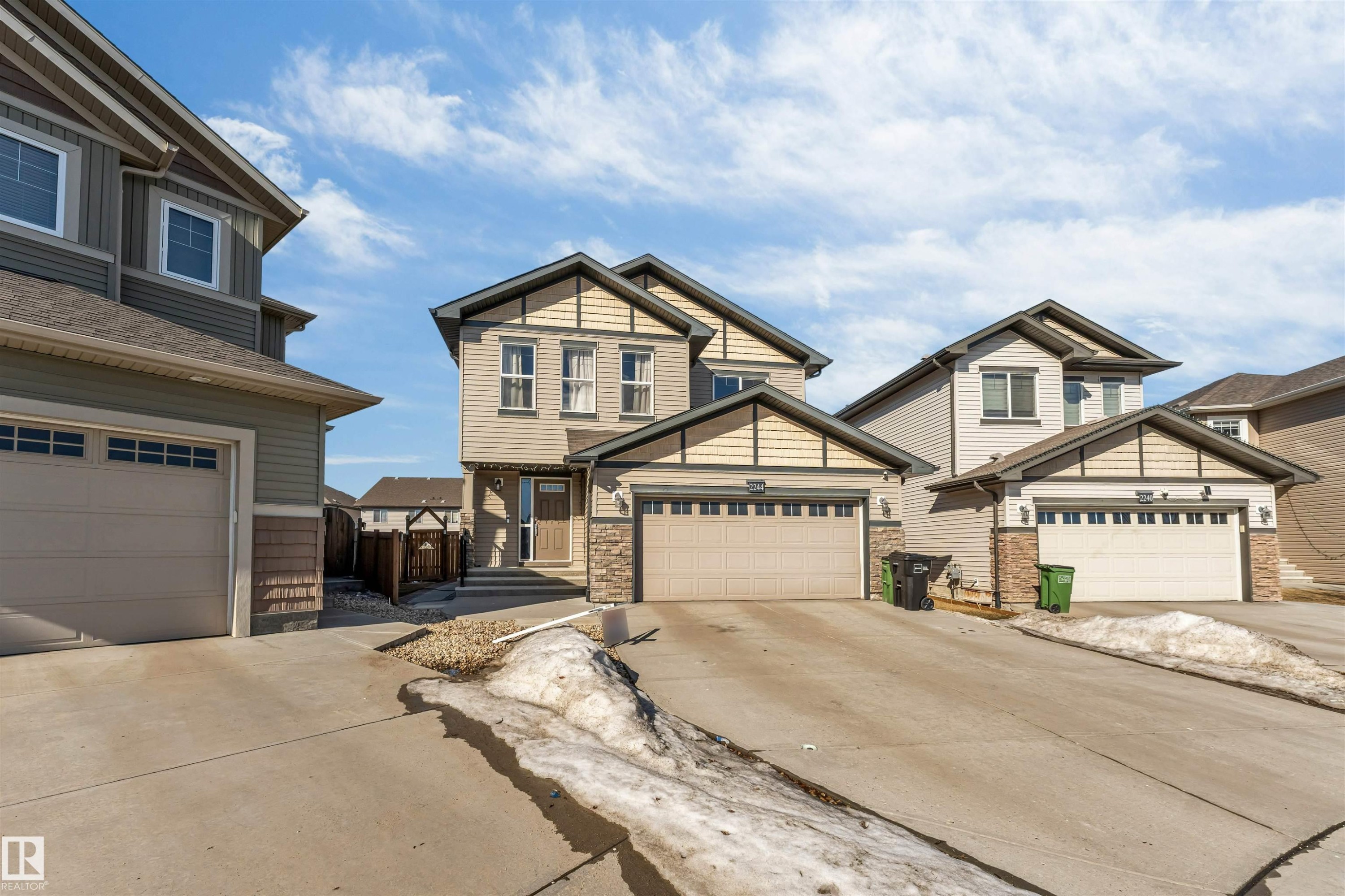 The property features an attached garage with a concrete driveway and an exterior clad in siding with stone accents - 2244 21 Avenue, Edmonton, AB - Outdoor With Facade