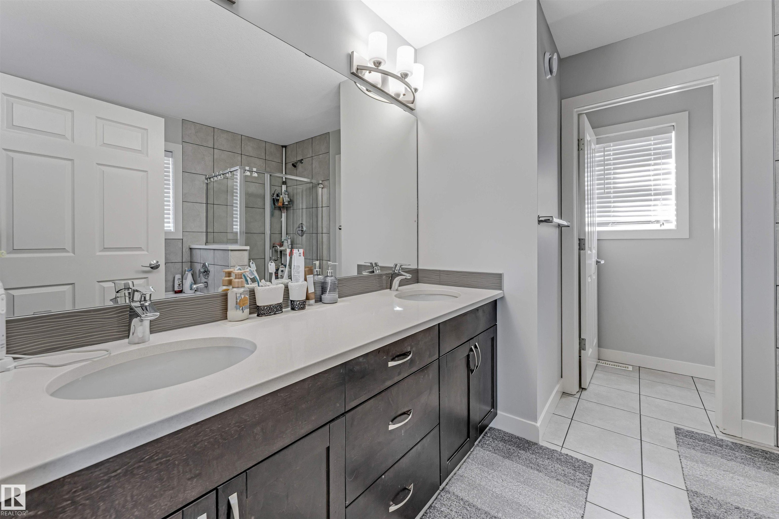 Bathroom featuring a double vanity with white countertops, dark wood cabinetry, and a large mirror - 2244 21 Avenue, Edmonton, AB - Indoor Photo Showing Bathroom