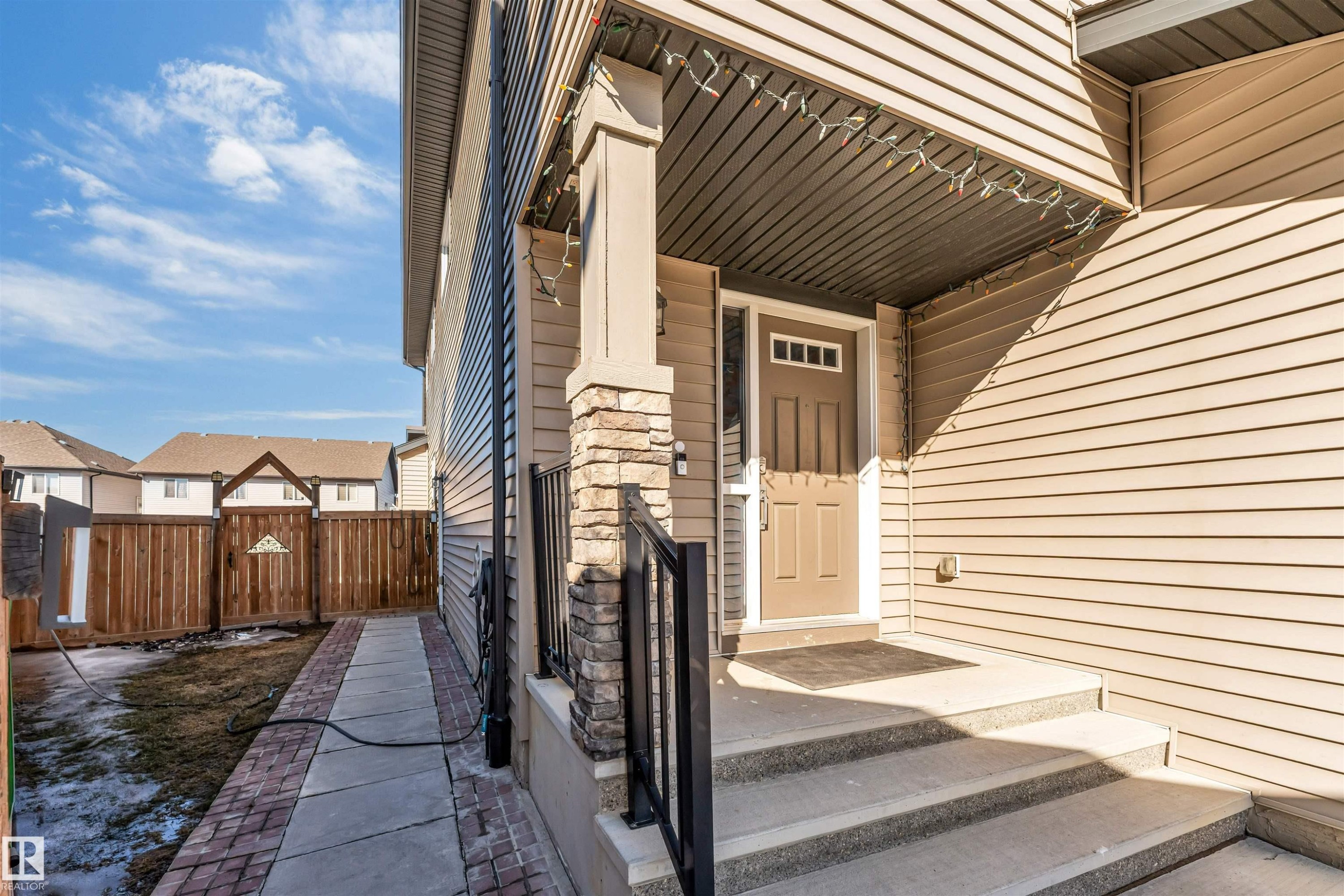 The property features a front entrance with concrete steps and a stone-clad pillar, leading to a brown entry door with decorative glass inserts - 2244 21 Avenue, Edmonton, AB - Outdoor