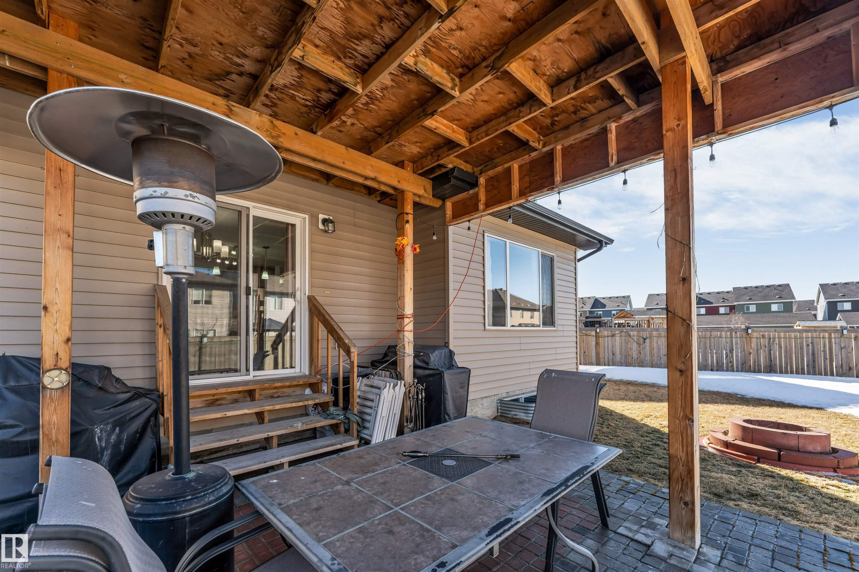 The property features a covered patio area with exposed wood beams, string lighting, and a paved surface - 2244 21 Avenue, Edmonton, AB - Outdoor With Deck Patio Veranda With Exterior