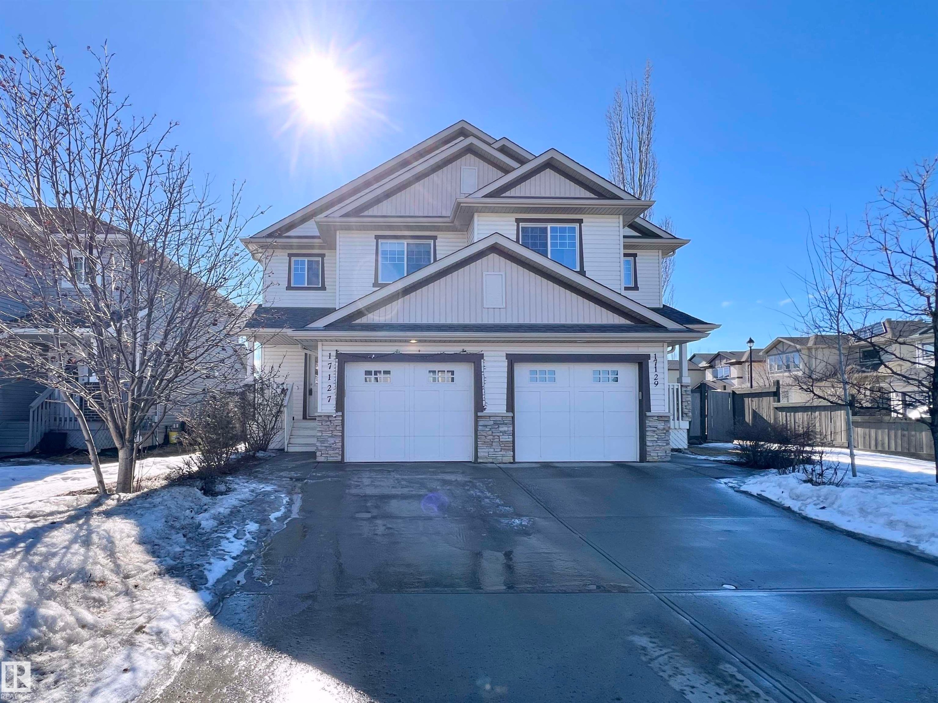 The property features two levels, a light-colored exterior with darker trim, and two garage doors with window accents - 17127 7A Avenue, Edmonton, AB - Outdoor With Facade