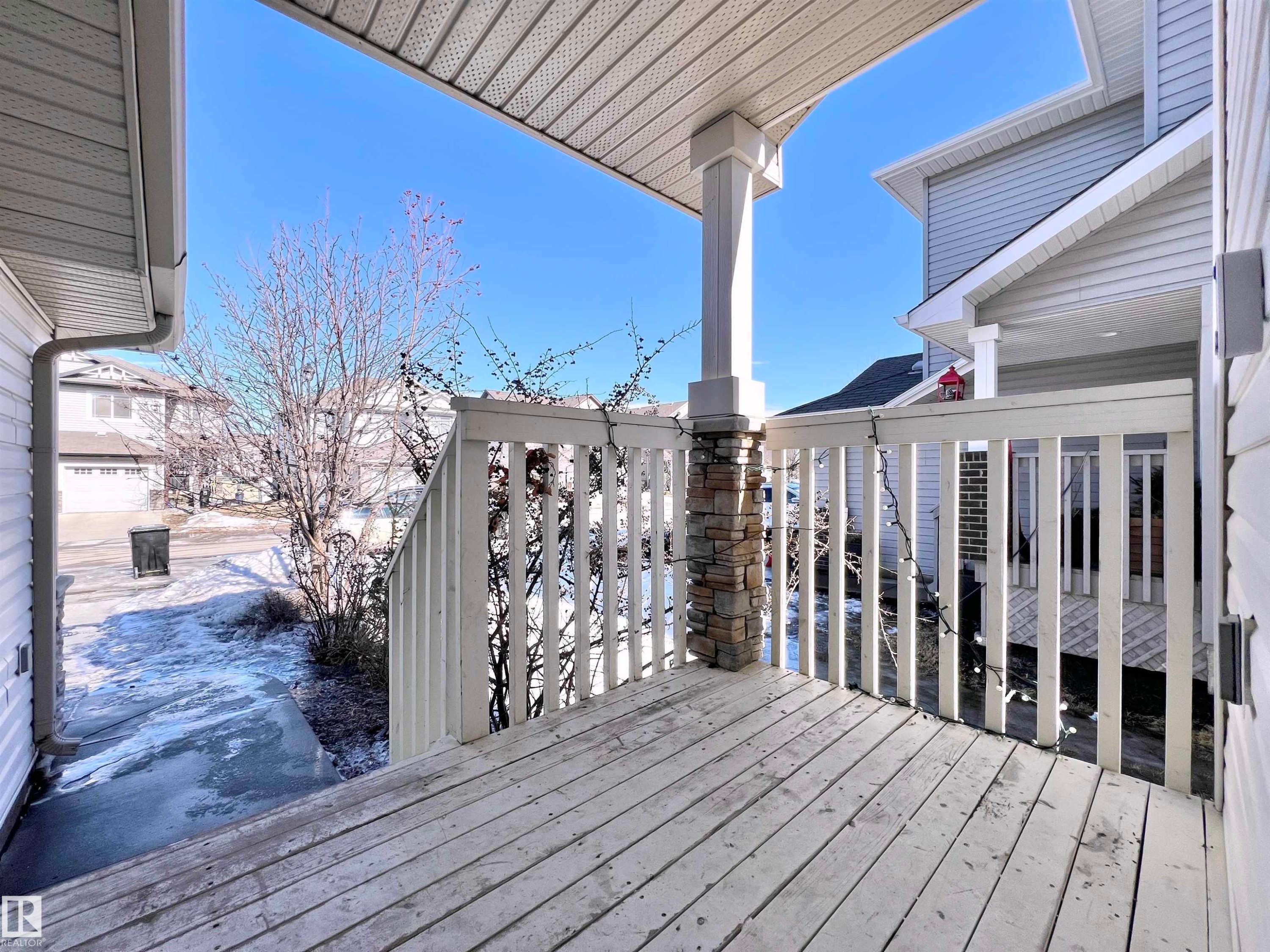 Welcoming front porch featuring a wooden deck and a stone-clad pillar - 17127 7A Avenue, Edmonton, AB - Outdoor With Deck Patio Veranda With Exterior
