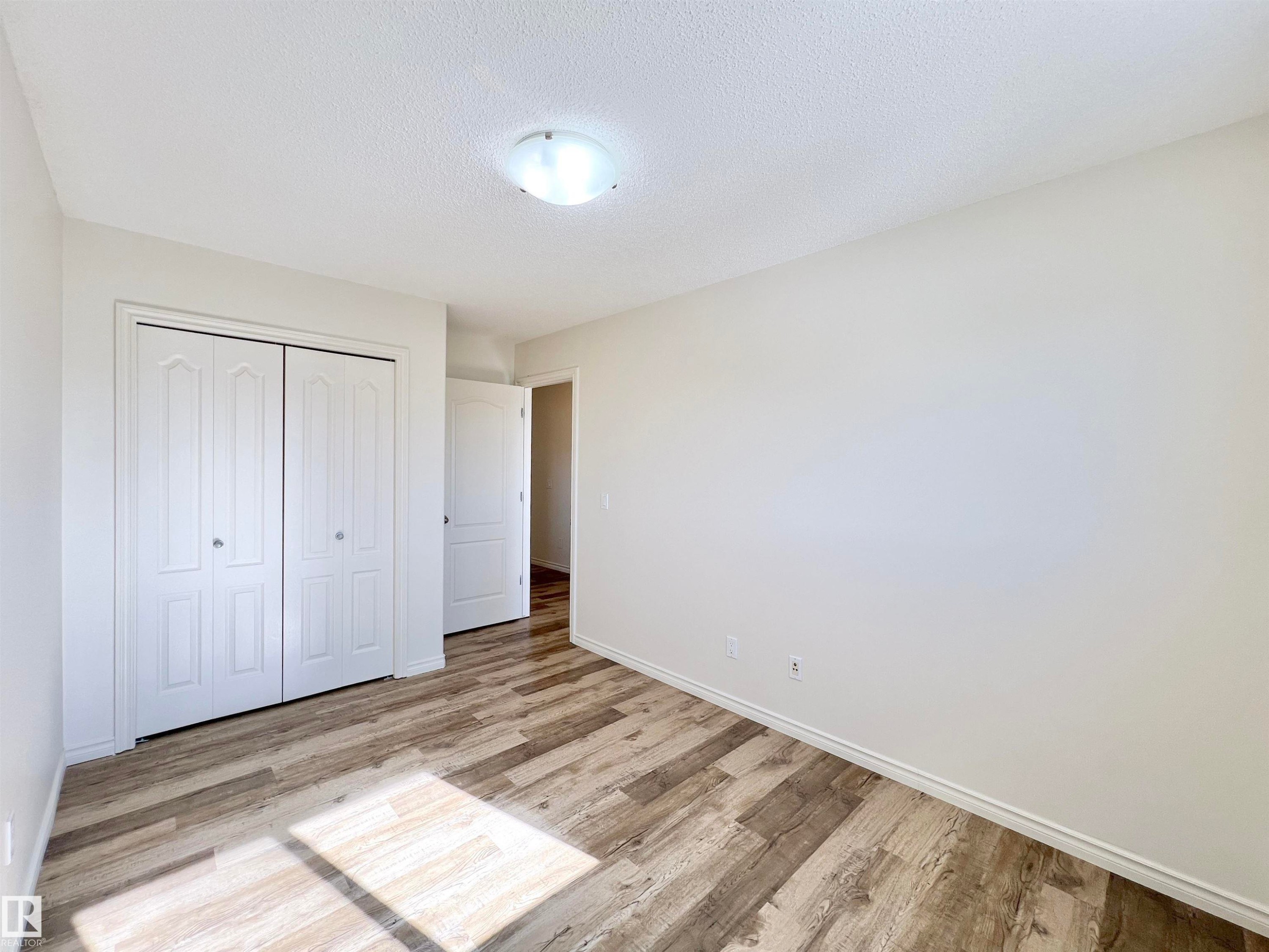 This property features a room with light-colored walls and wood-look flooring - 17127 7A Avenue, Edmonton, AB - Indoor Photo Showing Other Room
