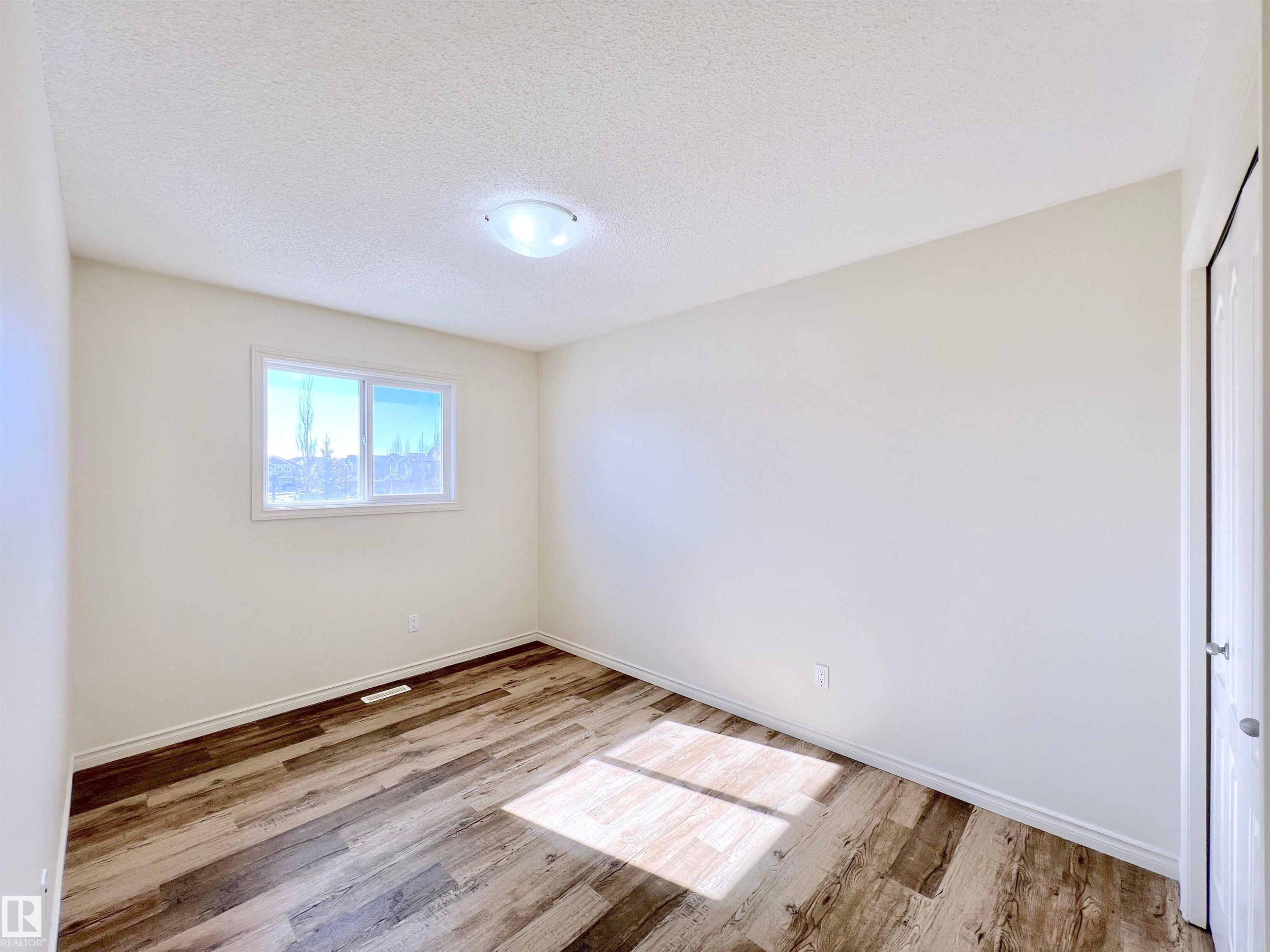 This room features light-colored walls, wood-style flooring, and a window providing natural light - 17127 7A Avenue, Edmonton, AB - Indoor Photo Showing Other Room