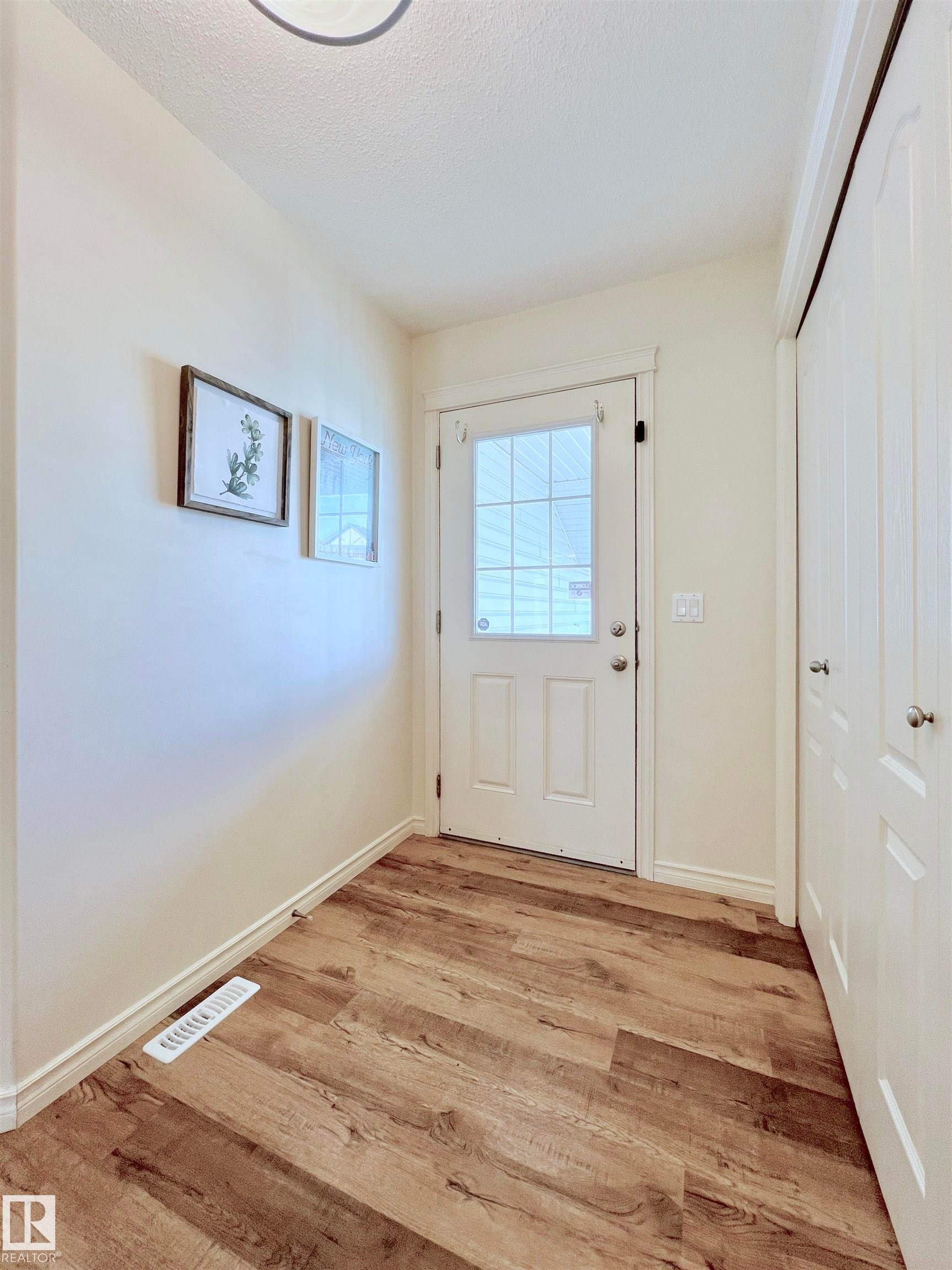 The entryway features wood-look flooring, a white paneled door with a window, and white walls - 17127 7A Avenue, Edmonton, AB - Indoor Photo Showing Other Room