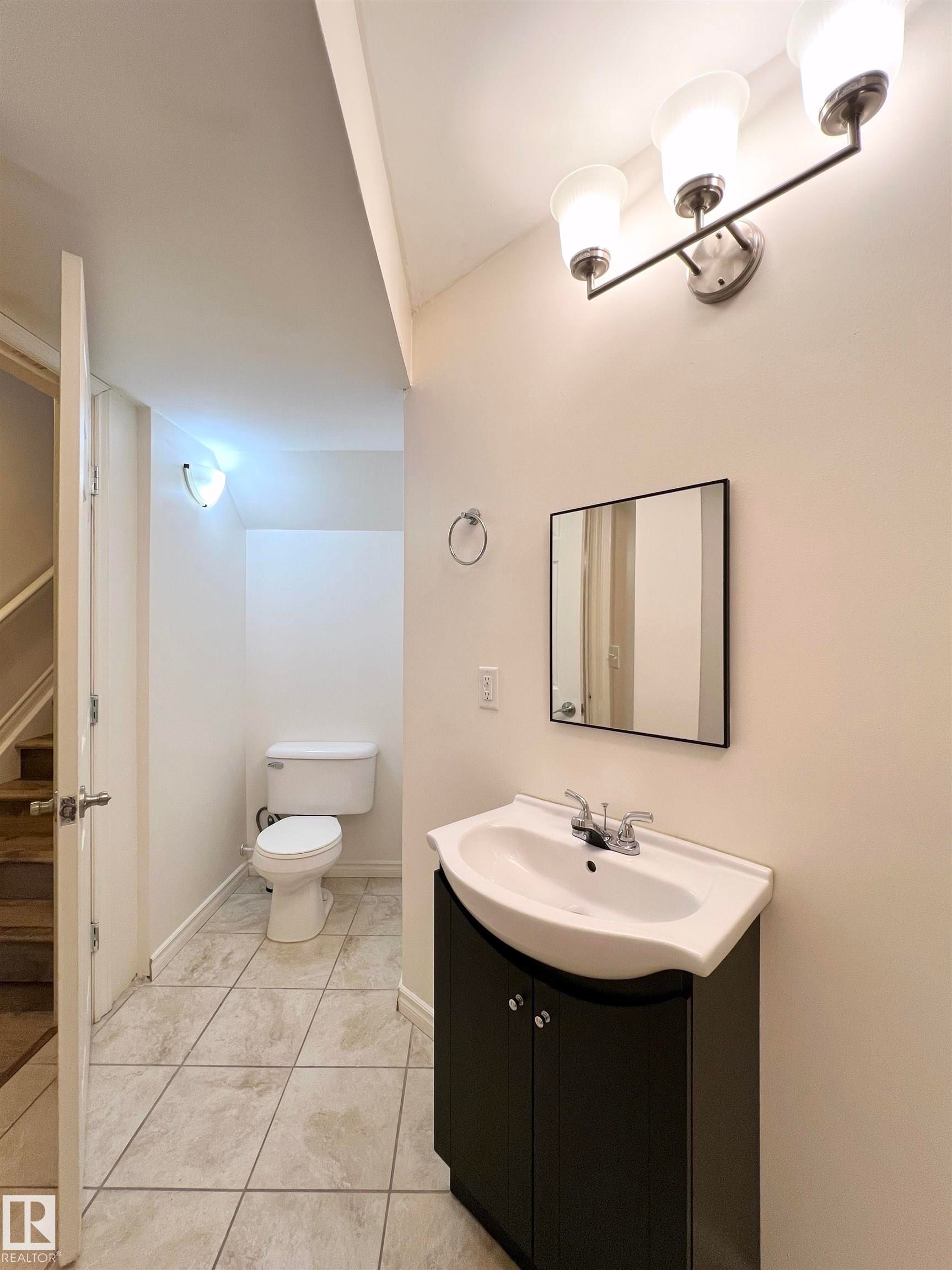 Bathroom featuring a vanity with a dark cabinet, a white sink, and a wall-mounted mirror - 17127 7A Avenue, Edmonton, AB - Indoor Photo Showing Bathroom