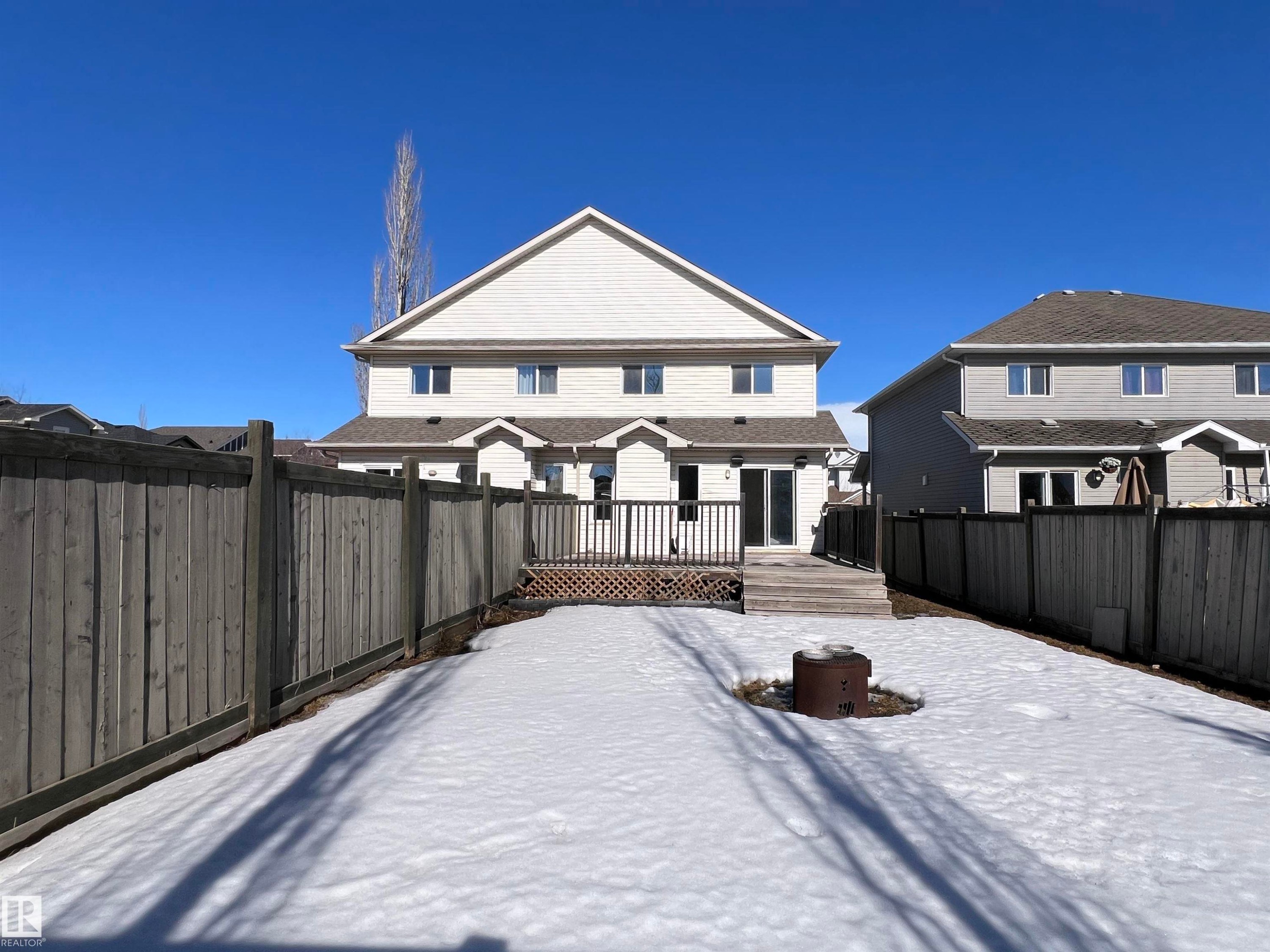 The property features a private backyard with a wooden fence and a spacious wooden deck with railings - 17127 7A Avenue, Edmonton, AB - Outdoor With Deck Patio Veranda