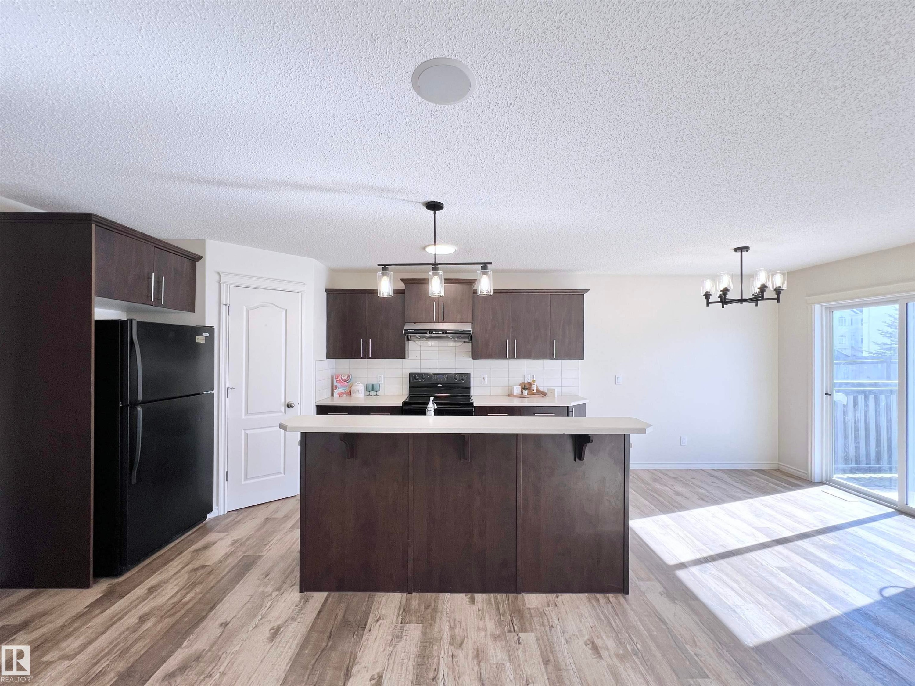 The property features an open-concept kitchen and living area with wood-look flooring - 17127 7A Avenue, Edmonton, AB - Indoor Photo Showing Kitchen