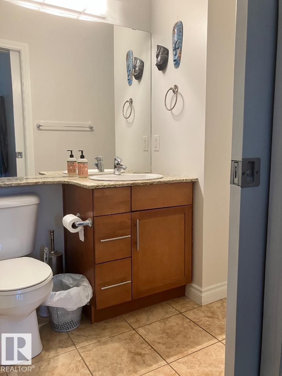 The bathroom features a vanity with a light-colored countertop, an undermount sink, and a wooden cabinet with drawers and a storage compartment - 145 10121 80 Avenue, Edmonton, AB - Indoor Photo Showing Bathroom