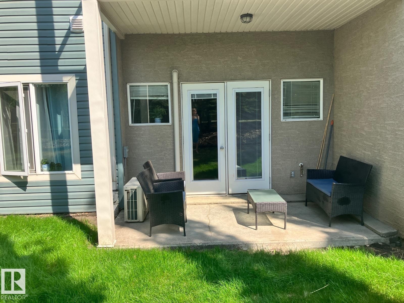 Outdoor patio area featuring a concrete surface, direct access through double doors, and a well-maintained lawn - 145 10121 80 Avenue, Edmonton, AB - Outdoor With Deck Patio Veranda With Exterior