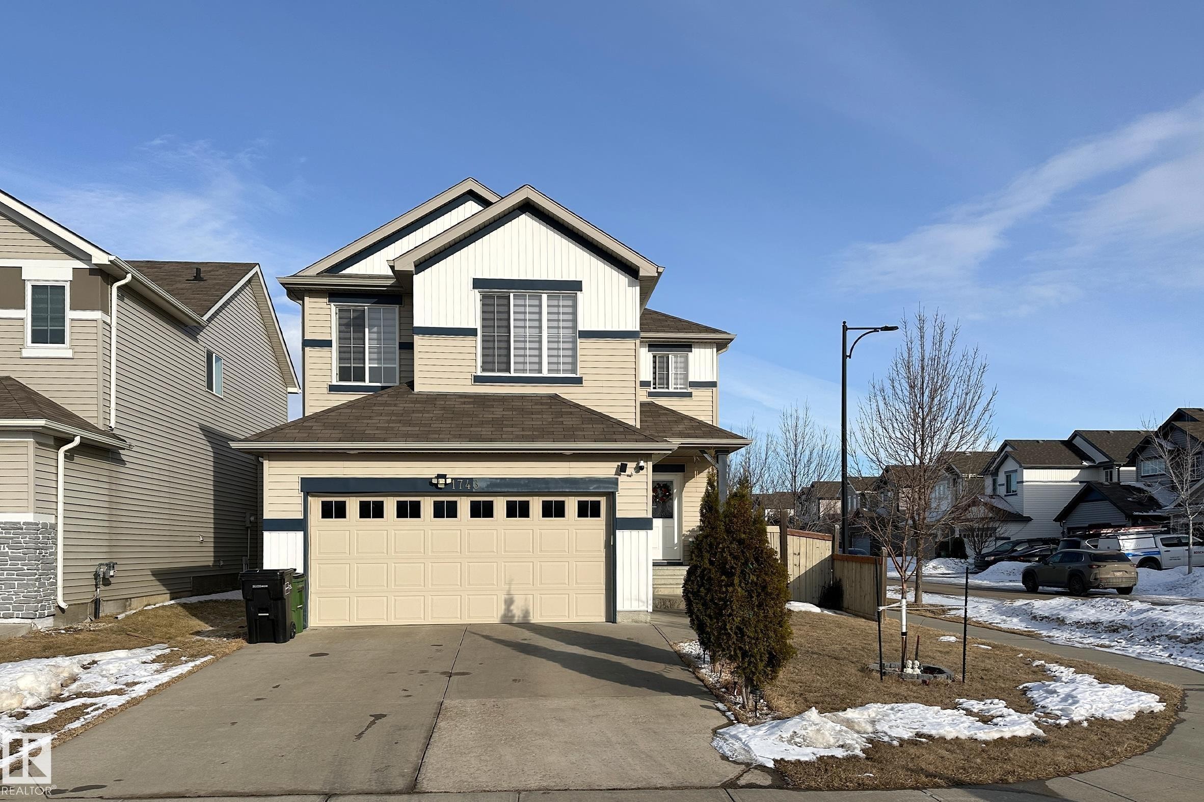 The property features a two-car garage, a paved driveway, and a front entrance with a small covered porch - 1743 60 Street Sw, Edmonton, AB - Outdoor