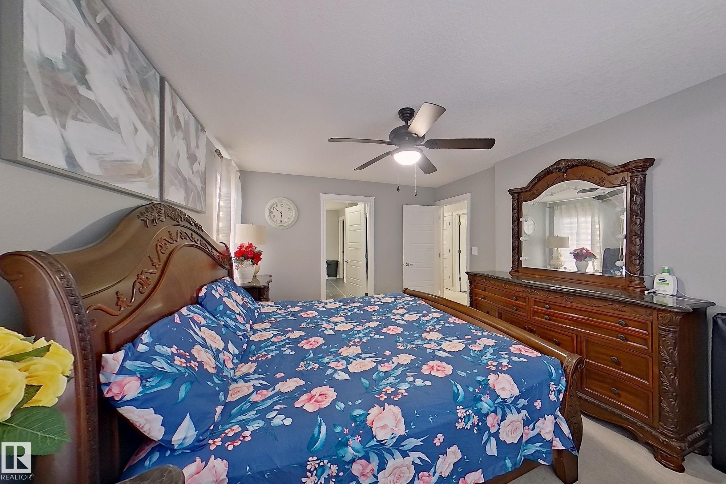 The bedroom features light gray walls, a ceiling fan, and a view into a hallway with a white door - 1743 60 Street Sw, Edmonton, AB - Indoor Photo Showing Bedroom