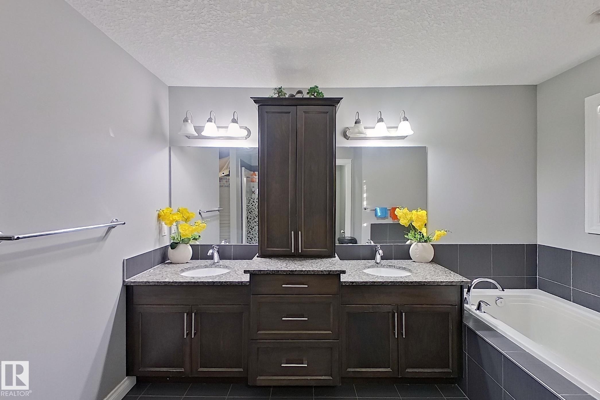 Bathroom featuring a double vanity with dark wood cabinetry, granite countertops, and two undermount sinks - 1743 60 Street Sw, Edmonton, AB - Indoor Photo Showing Bathroom