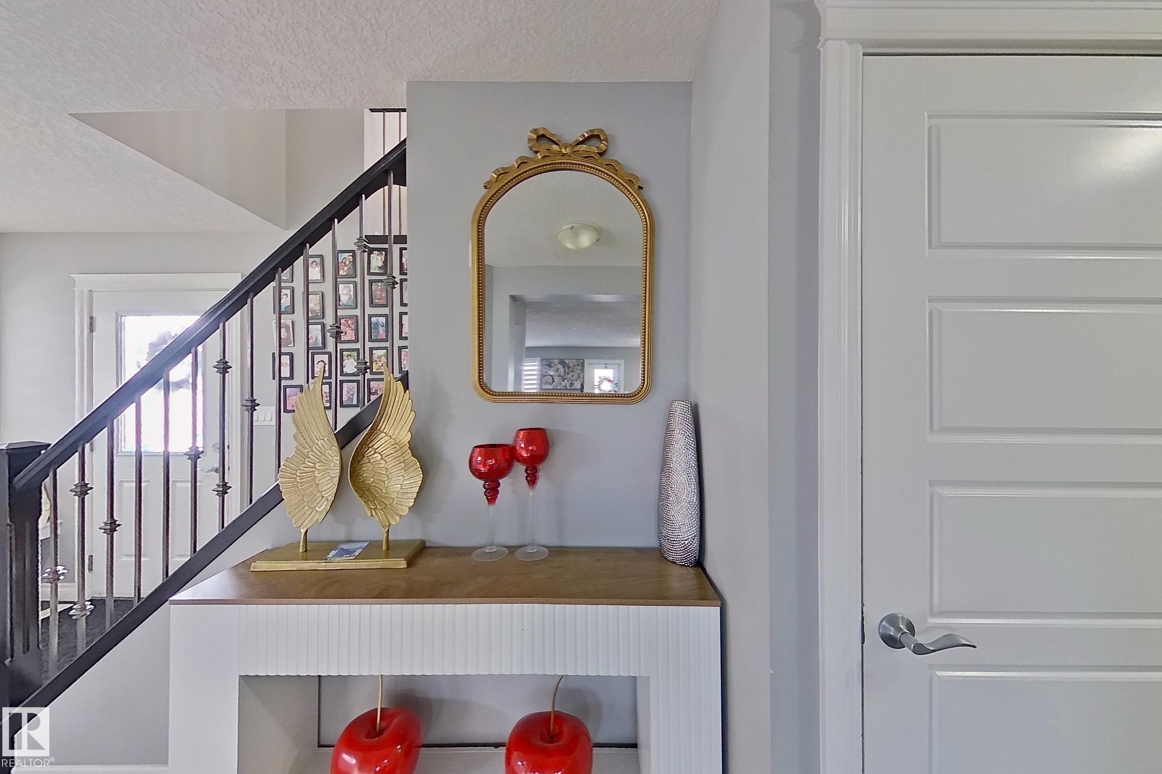 Entryway featuring a staircase with dark banisters, a console table, and a paneled door with a silver handle - 1743 60 Street Sw, Edmonton, AB - Indoor Photo Showing Other Room