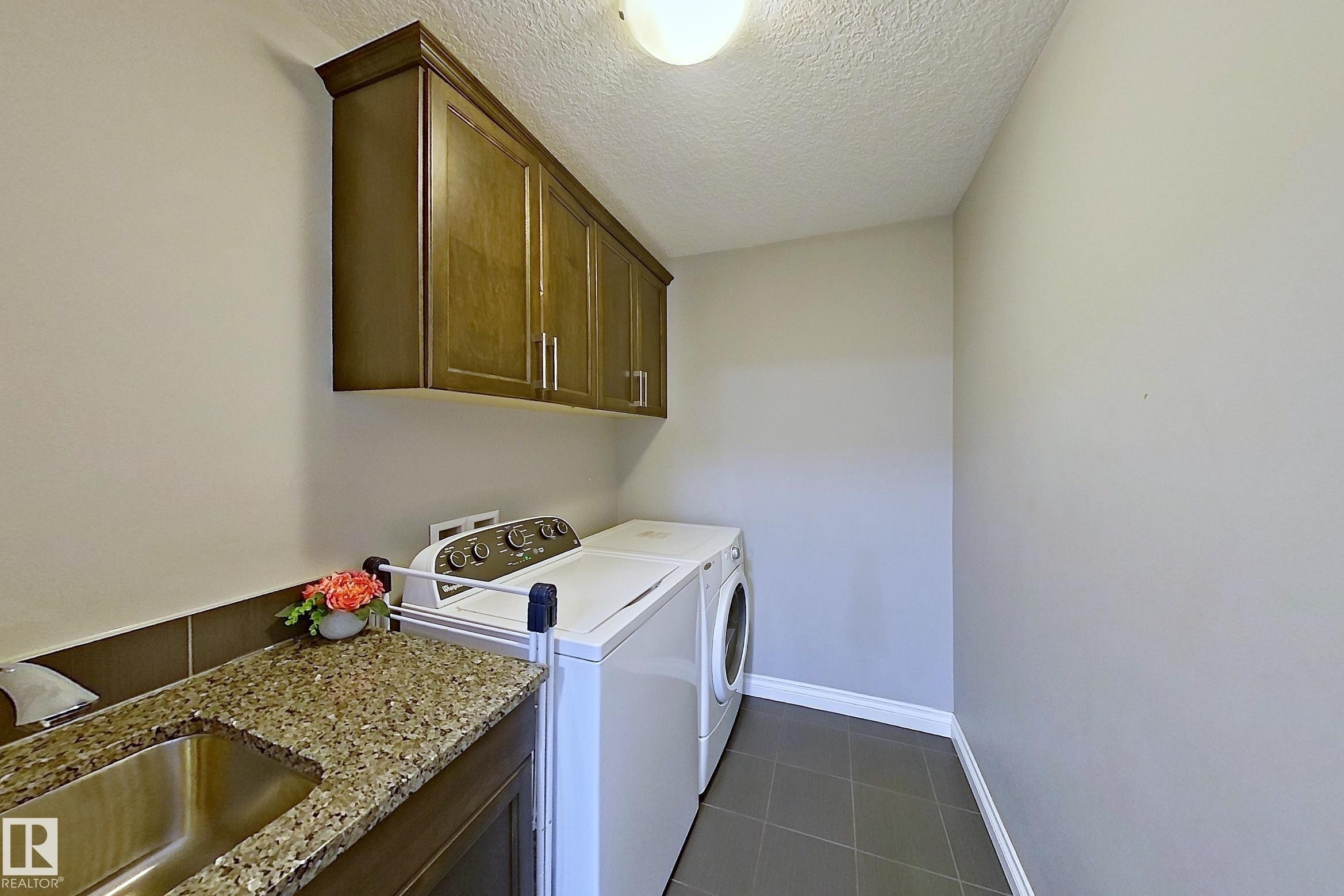 The laundry area features a stainless steel sink, granite countertops, and dark wood cabinetry - 1743 60 Street Sw, Edmonton, AB - Indoor Photo Showing Laundry Room