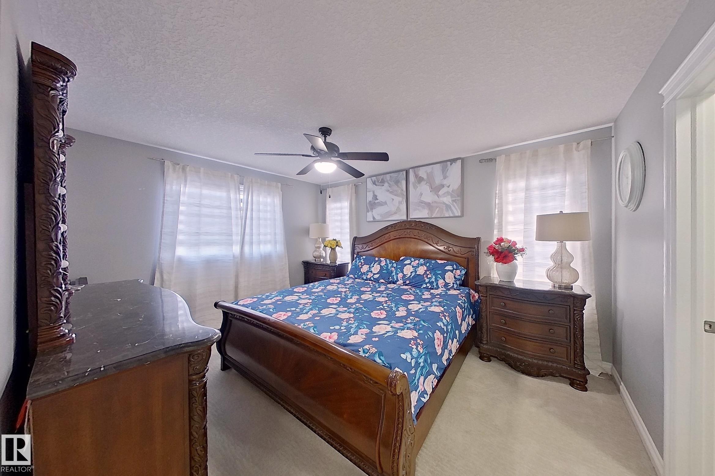 A spacious room featuring a ceiling fan, light gray wall paint, and white window coverings - 1743 60 Street Sw, Edmonton, AB - Indoor Photo Showing Bedroom