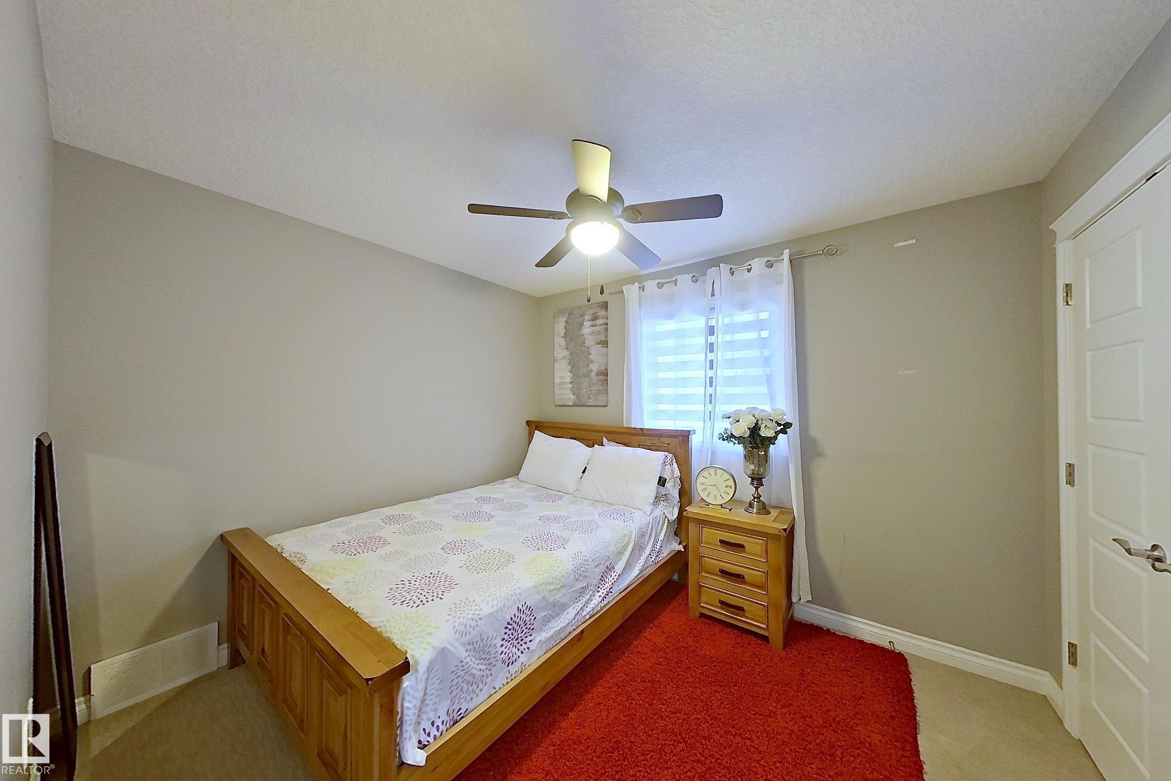 This room features a ceiling fan, a window with blinds and curtains, and a solid-panel door - 1743 60 Street Sw, Edmonton, AB - Indoor Photo Showing Bedroom