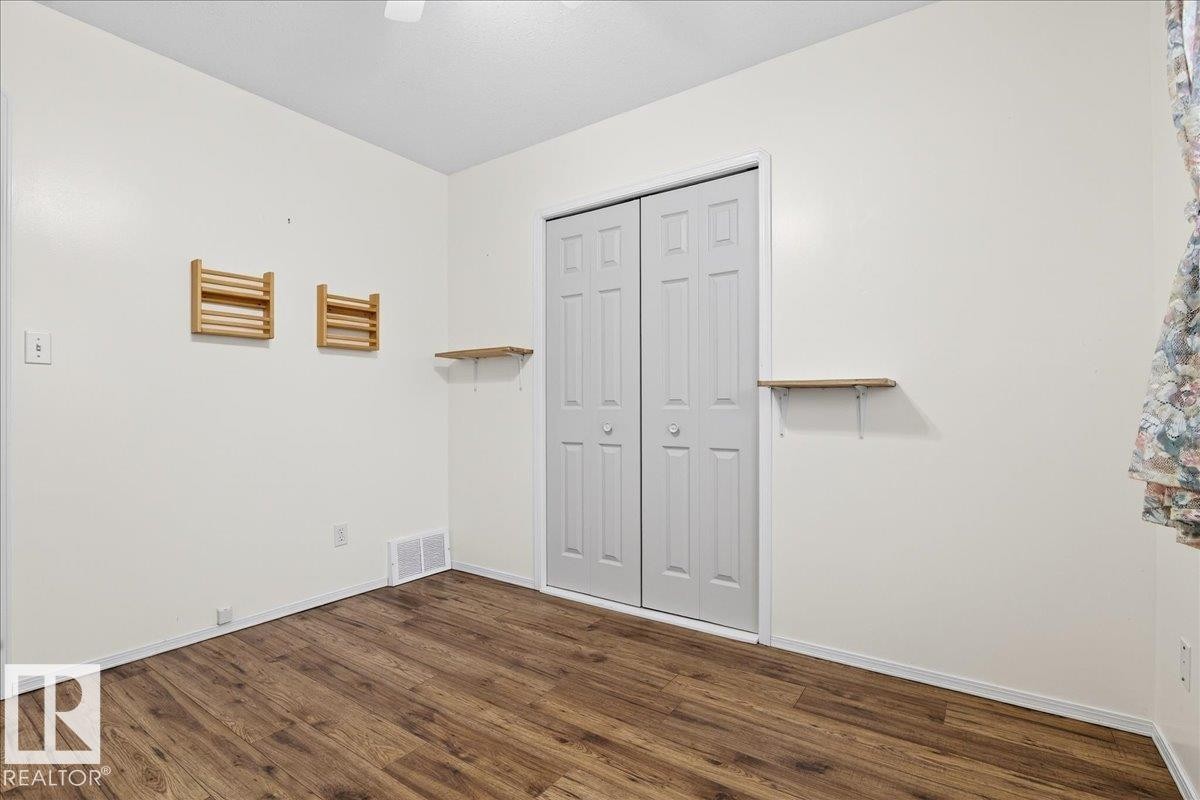 The room features dark wood-style flooring, white walls, and a white bi-fold closet door - 4412 Yeoman Close, Onoway, AB - Indoor Photo Showing Other Room