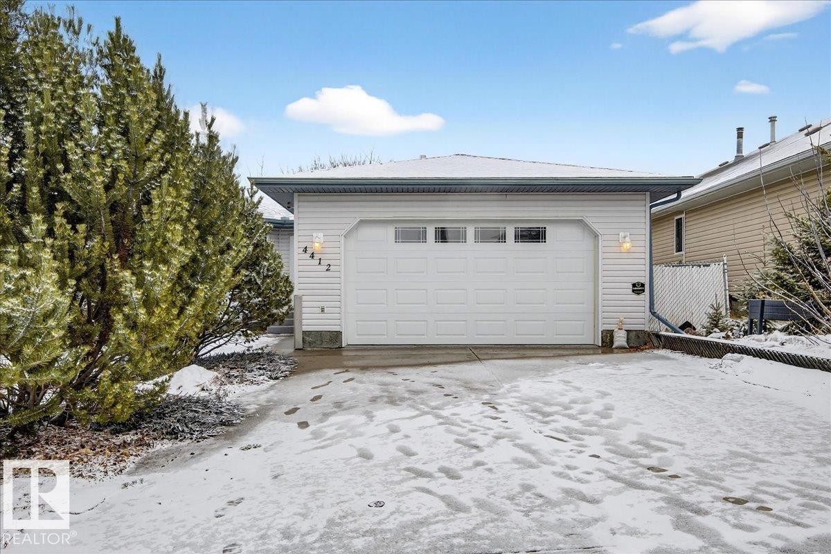 The property features a front-facing attached garage with a garage door that includes upper window panels - 4412 Yeoman Close, Onoway, AB - Outdoor With Exterior