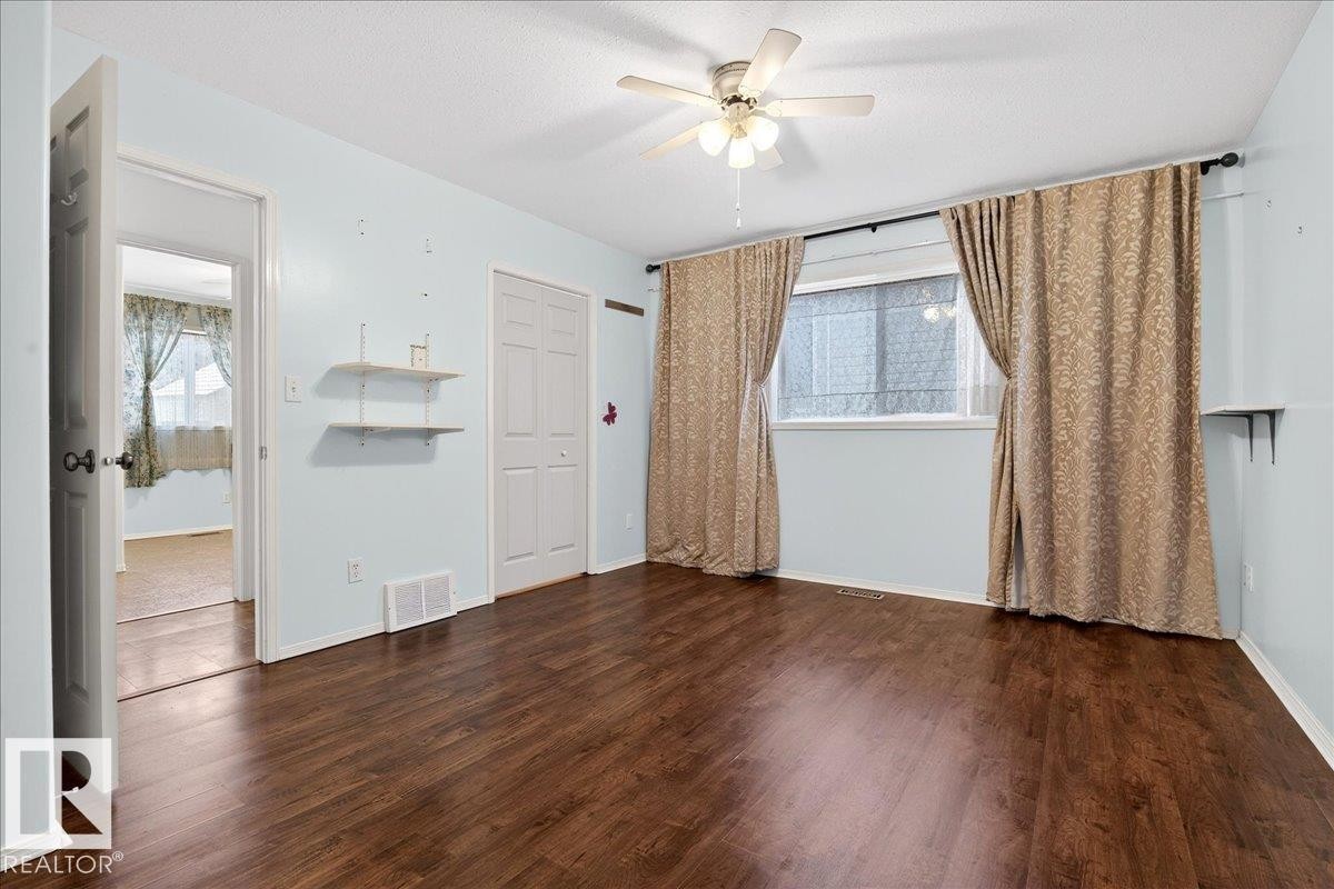 This room features dark hardwood flooring, light blue walls, a ceiling fan, and a window with light-colored curtains - 4412 Yeoman Close, Onoway, AB - Indoor Photo Showing Other Room