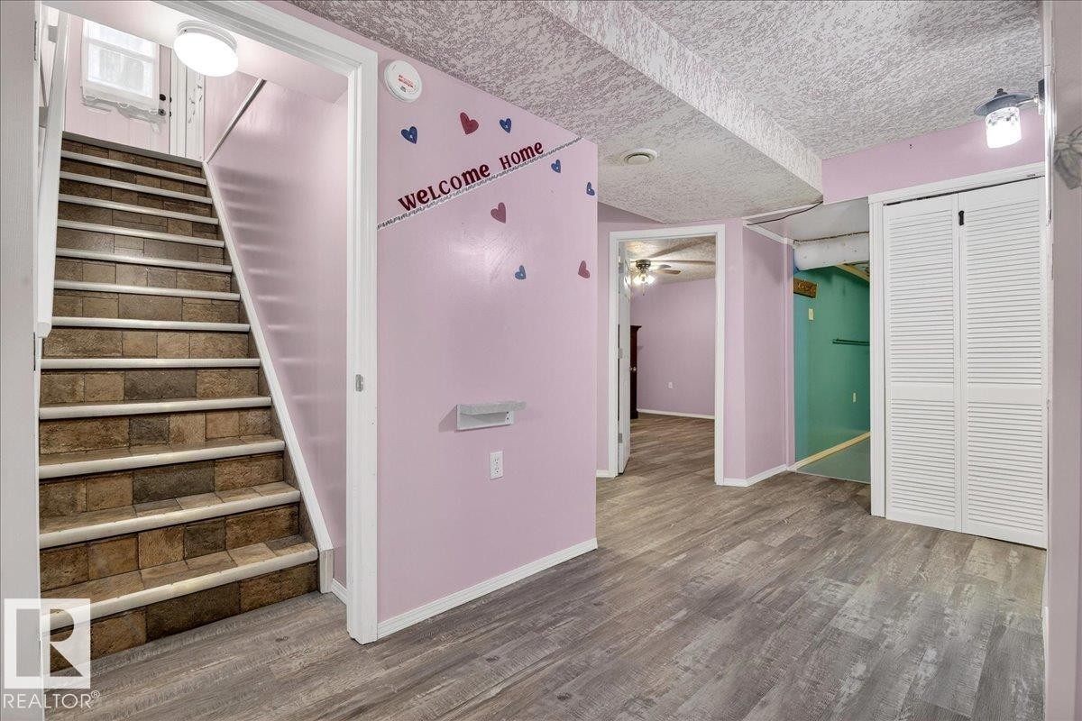 The interior features a staircase with tiled risers and treads, alongside an area with wood-look flooring - 4412 Yeoman Close, Onoway, AB - Indoor Photo Showing Other Room