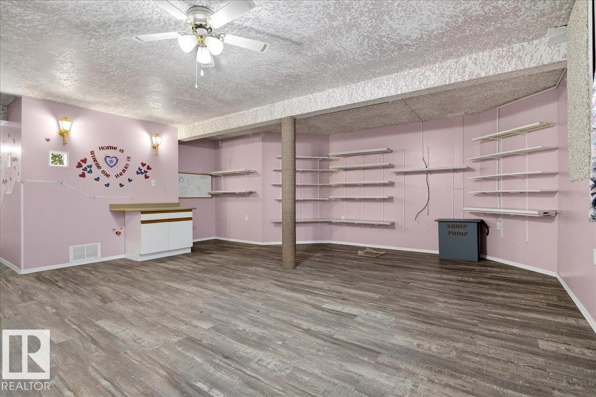 This spacious room features wood-look flooring, ceiling fan, and built-in shelving for storage - 4412 Yeoman Close, Onoway, AB - Indoor Photo Showing Other Room