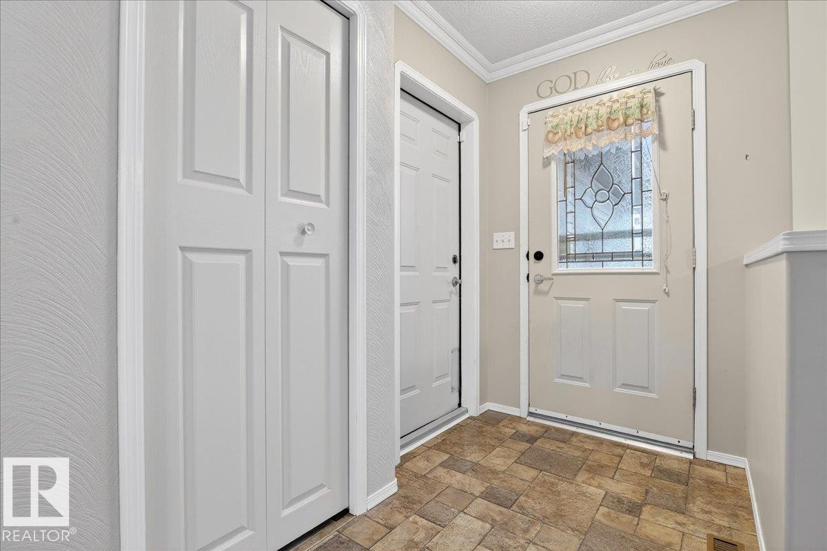 Entryway featuring patterned floor tiles, a white door with a decorative glass insert, and a white bi-fold door - 4412 Yeoman Close, Onoway, AB - Indoor Photo Showing Other Room