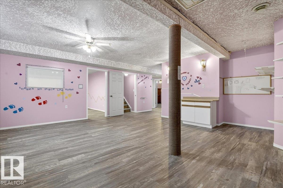 Spacious room featuring wood-look flooring, light pink walls, and a ceiling fan - 4412 Yeoman Close, Onoway, AB - Indoor Photo Showing Other Room