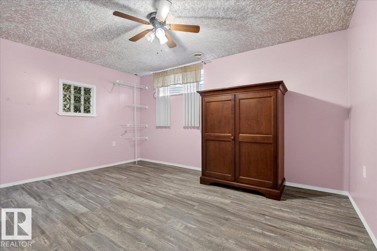This room features wood-look flooring, light pink walls, and a ceiling fan with light fixture - 4412 Yeoman Close, Onoway, AB - Indoor Photo Showing Other Room