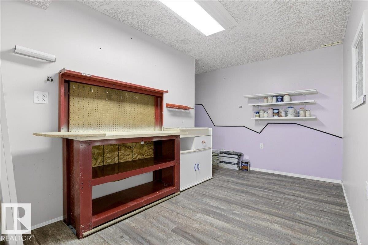 This versatile area features light gray walls, a red workbench with pegboard backing, and gray flooring - 4412 Yeoman Close, Onoway, AB - Indoor Photo Showing Other Room