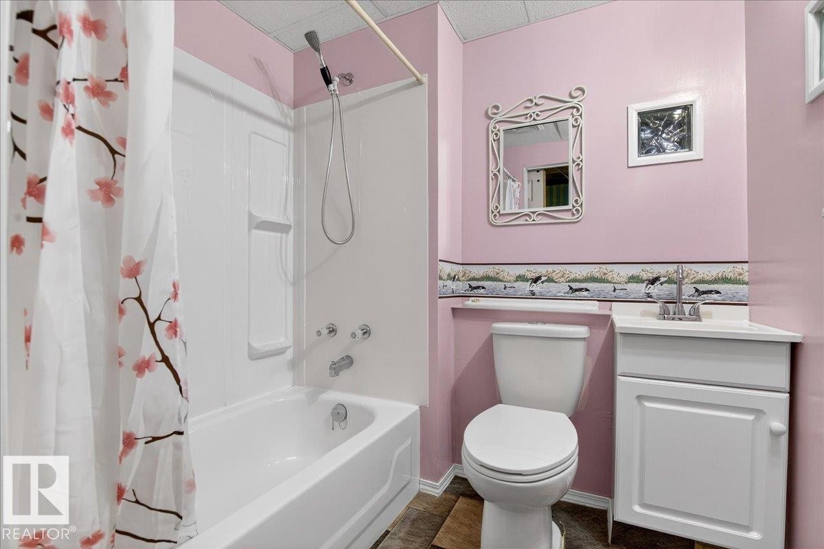 The bathroom features a white bathtub with a shower, a white toilet, and a white vanity with a silver faucet - 4412 Yeoman Close, Onoway, AB - Indoor Photo Showing Bathroom