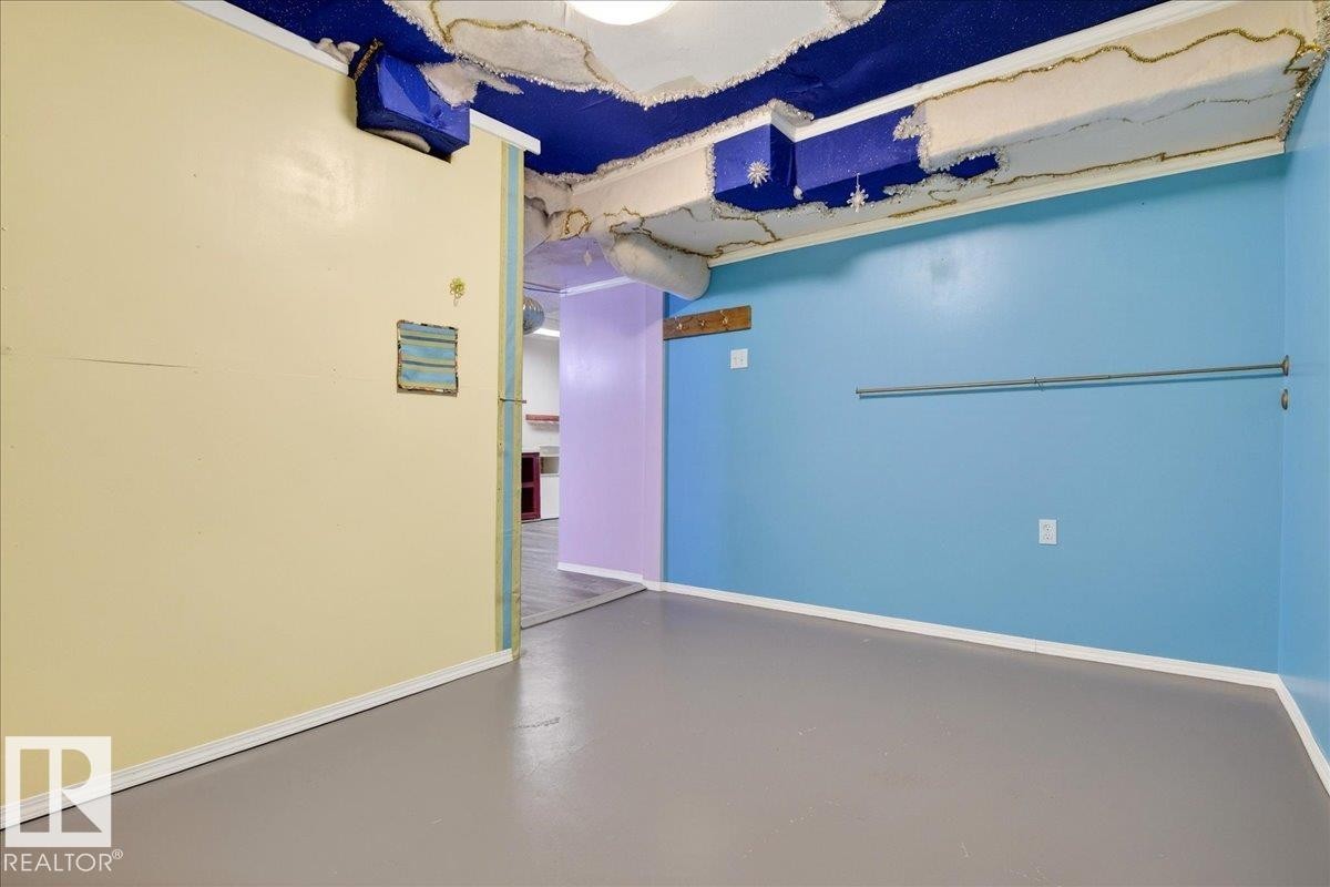 Spacious interior featuring a blue accent wall, light yellow wall, and grey flooring - 4412 Yeoman Close, Onoway, AB - Photo Showing Other Room