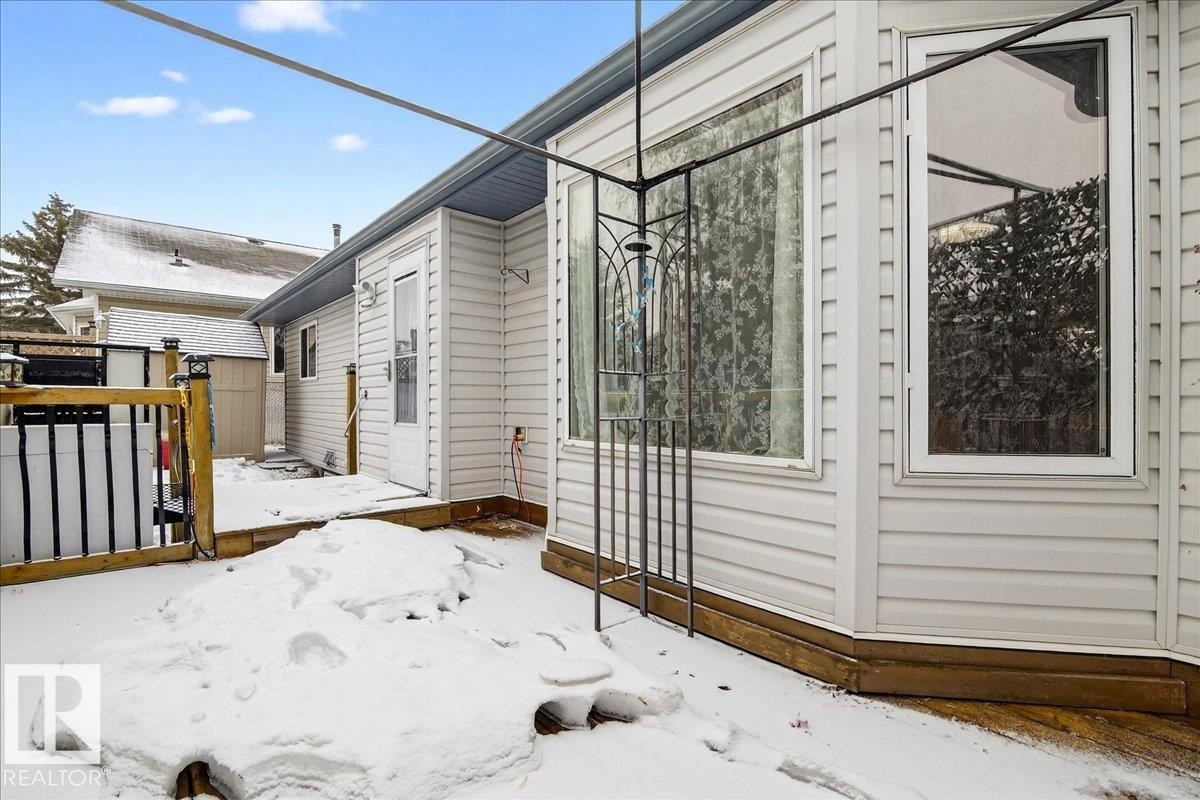The property features a white exterior with siding, a wooden deck, and a white back door - 4412 Yeoman Close, Onoway, AB - Outdoor With Exterior