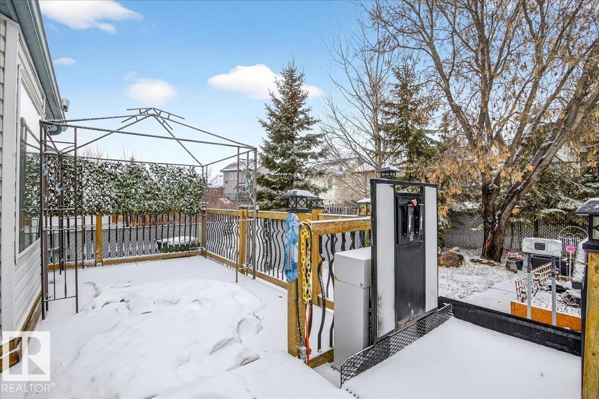 Expansive outdoor deck with a metal gazebo frame and wooden railings, overlooking a yard with mature trees - 4412 Yeoman Close, Onoway, AB - Outdoor