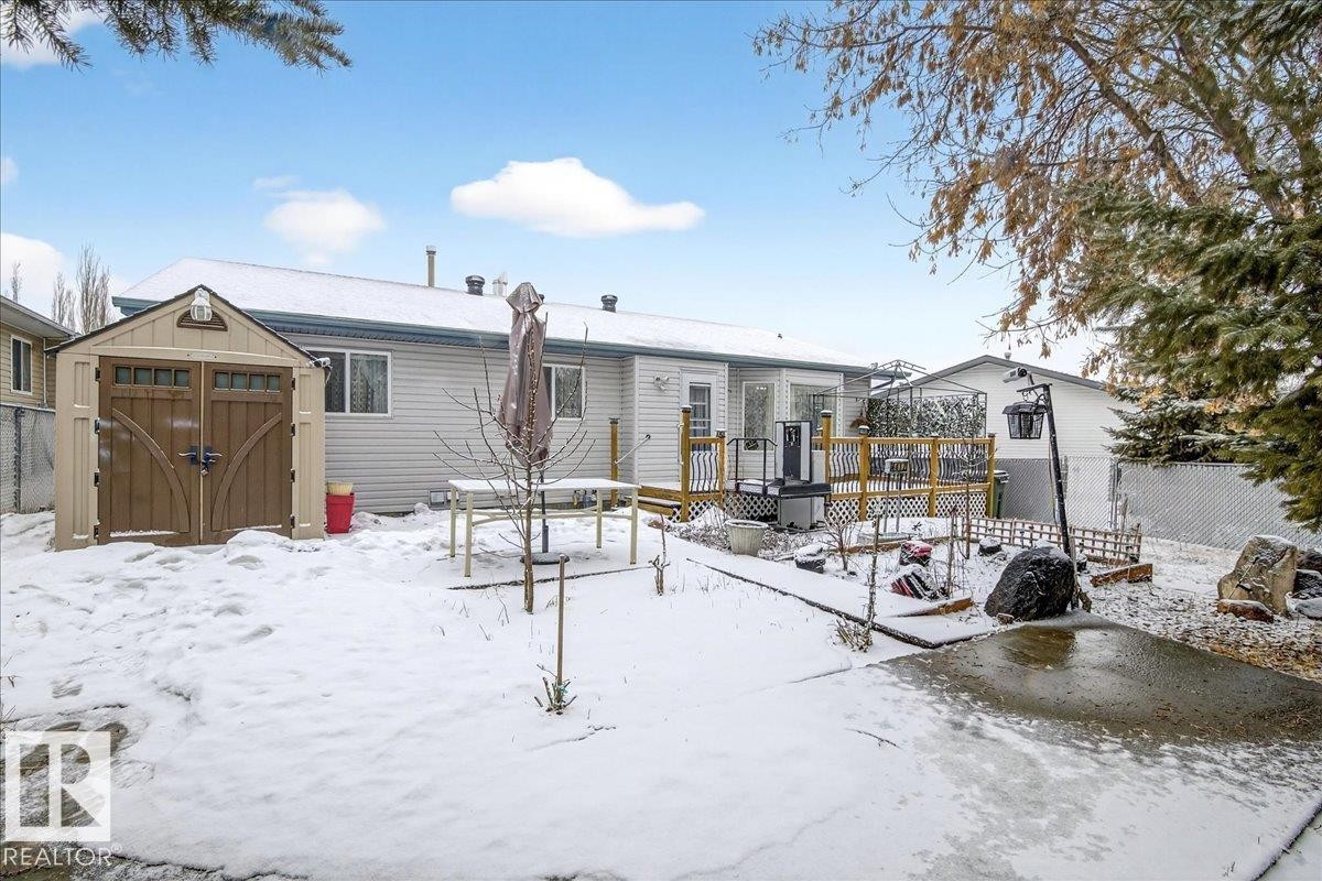 The property features a spacious rear yard with a wooden deck, a storage shed, and a paved area - 4412 Yeoman Close, Onoway, AB - Outdoor