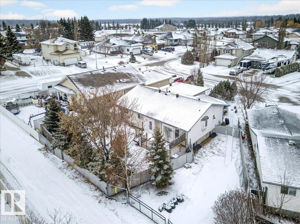 The property features a fenced yard with mature trees and a rear deck - 4412 Yeoman Close, Onoway, AB - Outdoor With View