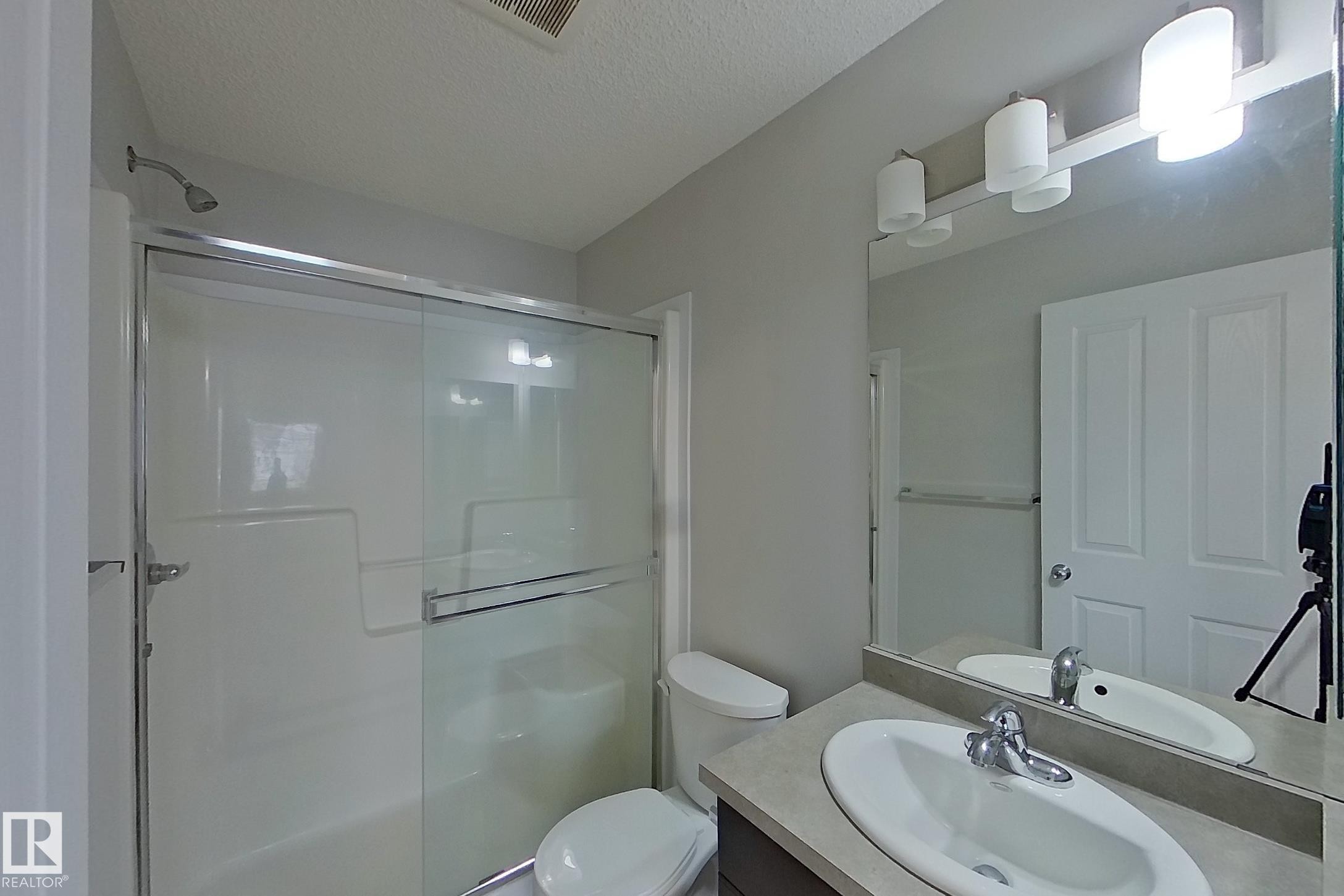 Well-appointed bathroom featuring a shower with sliding glass doors, a vanity with an integrated sink and chrome faucet, and overhead lighting - 87 4050 Savaryn Drive, Edmonton, AB - Indoor Photo Showing Bathroom