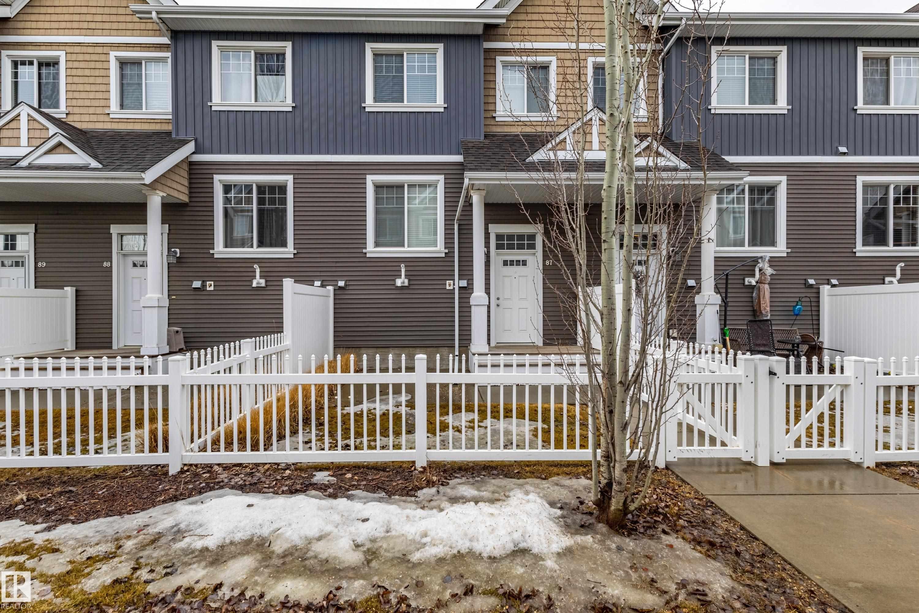 The property features a charming front entrance with a white picket fence and a paved walkway - 87 4050 Savaryn Drive, Edmonton, AB - Outdoor With Facade