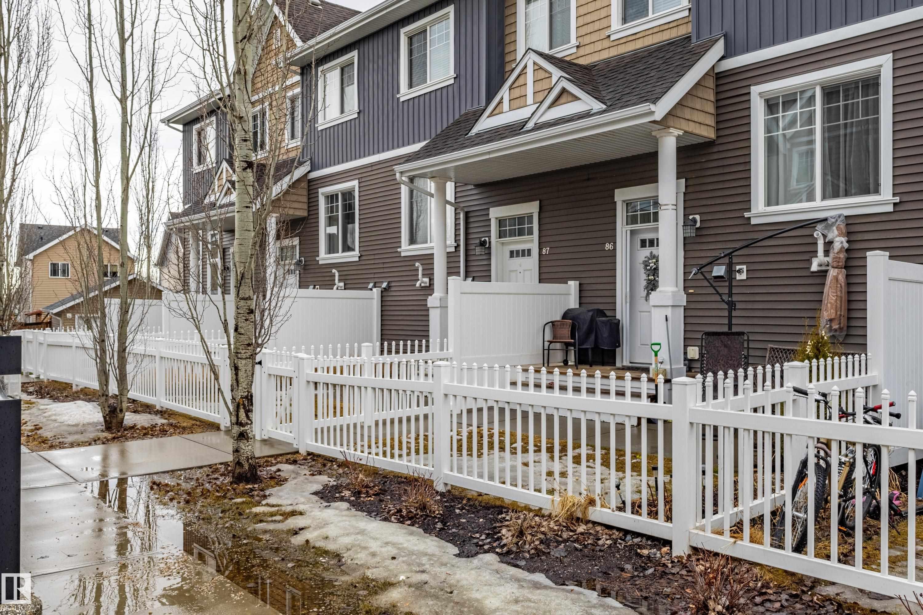 The property features a brown exterior with white window frames and a white picket fence - 87 4050 Savaryn Drive, Edmonton, AB - Outdoor
