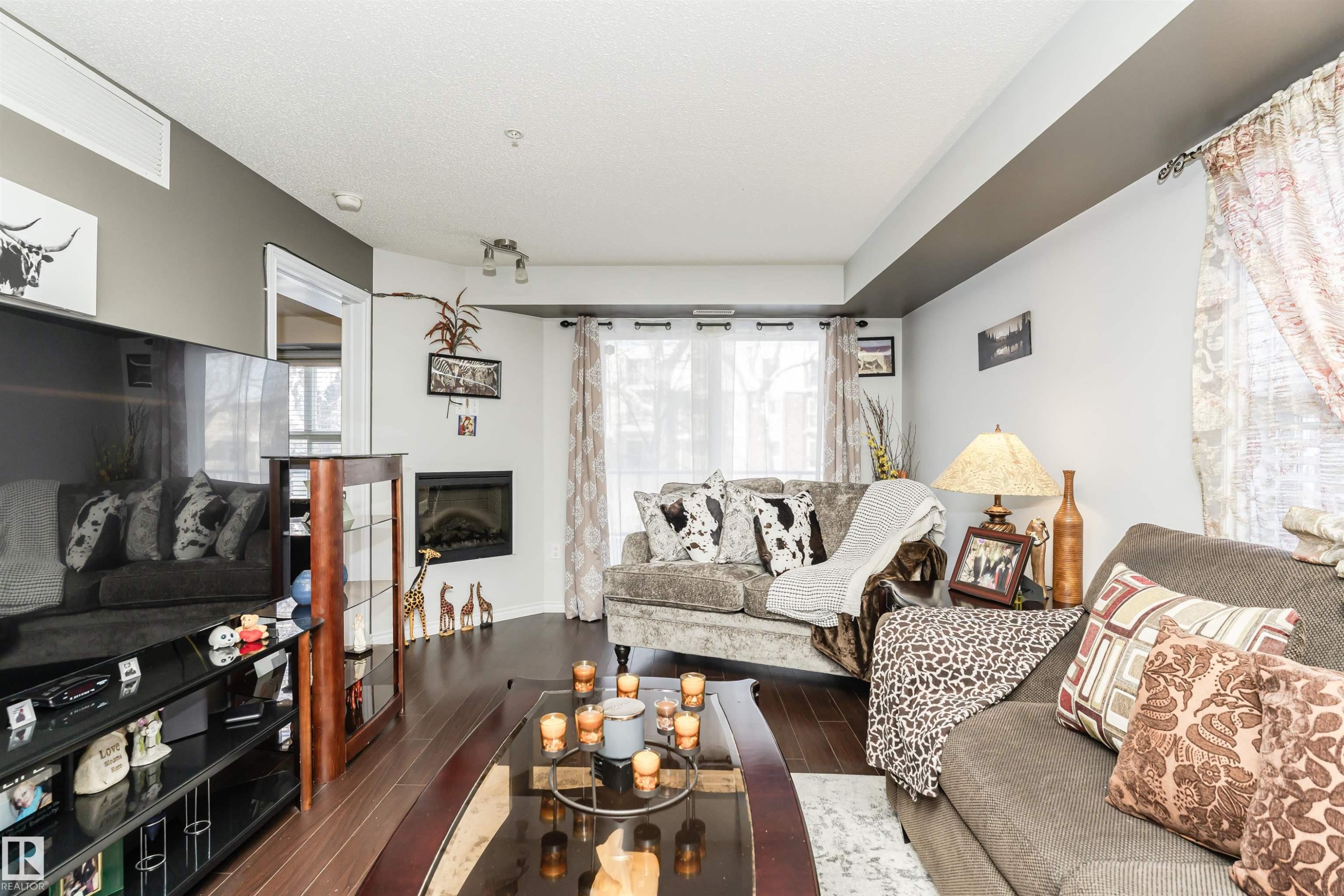 Living area featuring dark hardwood floors, a corner fireplace, and light-colored walls - 107 10118 106 Avenue, Edmonton, AB - Indoor Photo Showing Living Room