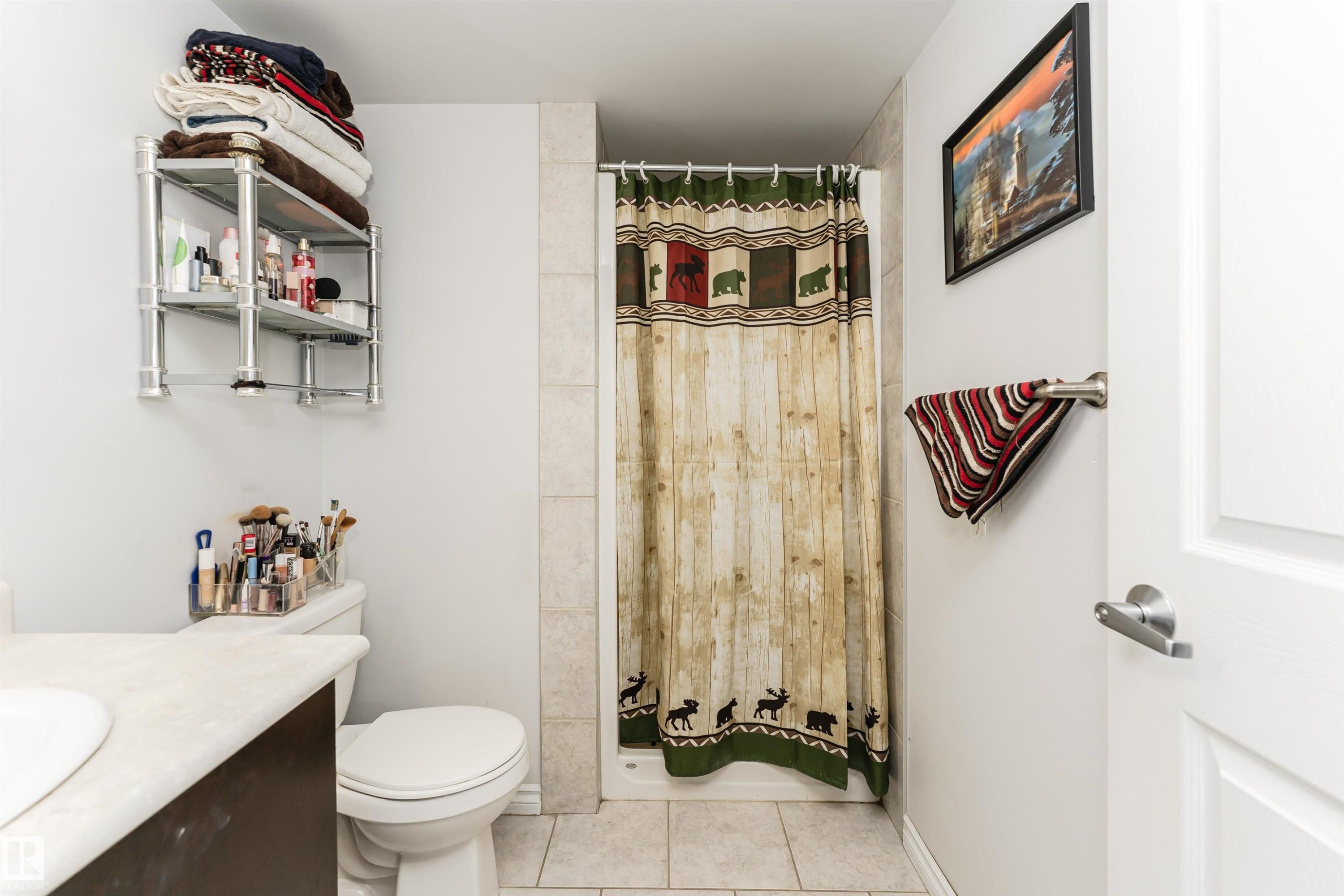 Bathroom featuring a shower with tiled walls, a toilet, and a vanity with a light-colored countertop and an integrated sink - 107 10118 106 Avenue, Edmonton, AB - Indoor Photo Showing Bathroom