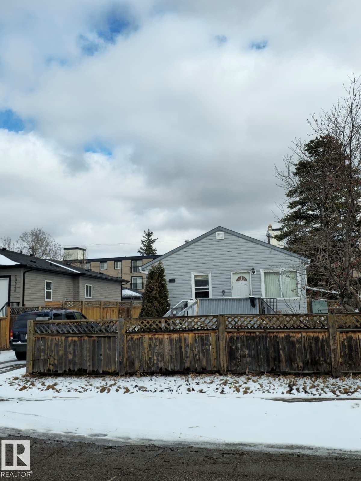 The property features a light-colored siding exterior, a front door with a window, and a deck accessible by stairs - 10541 157 Street, Edmonton, AB - Outdoor
