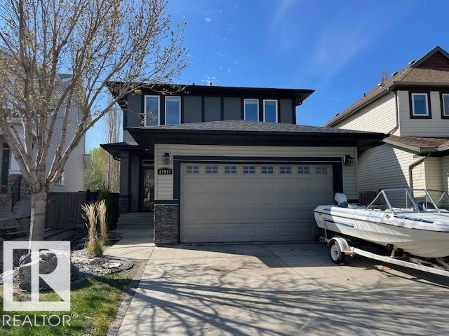 Modern exterior featuring a two-car garage, stone accents, and a covered entry - 21917 95A Avenue, Edmonton, AB - Outdoor With Facade