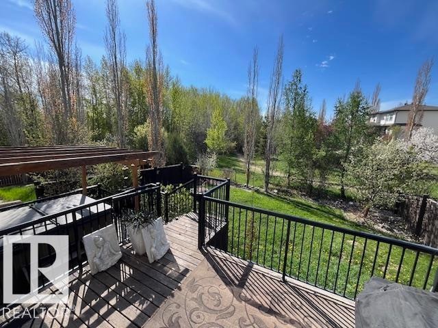 Spacious wood deck featuring a black metal railing, overhead pergola structure, and an integrated hot tub - 21917 95A Avenue, Edmonton, AB - Outdoor