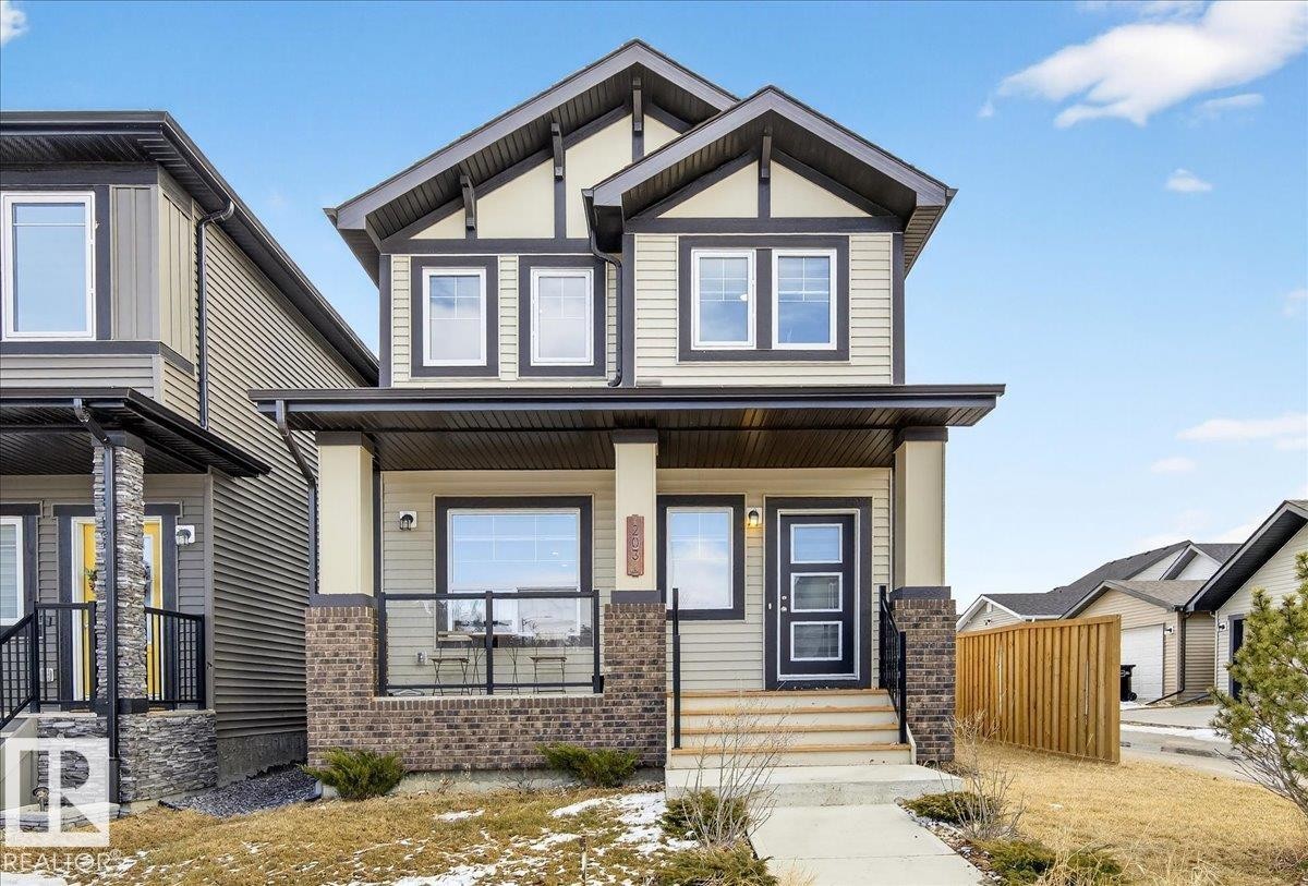 The property features a two-story exterior with light-colored siding and dark trim - 203 Cavanagh Common, Edmonton, AB - Outdoor With Deck Patio Veranda With Facade