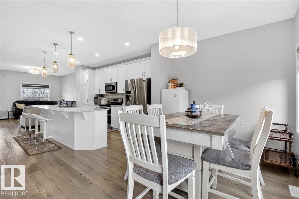 This property features an open concept kitchen and dining area with light hardwood flooring - 203 Cavanagh Common, Edmonton, AB - Indoor Photo Showing Dining Room