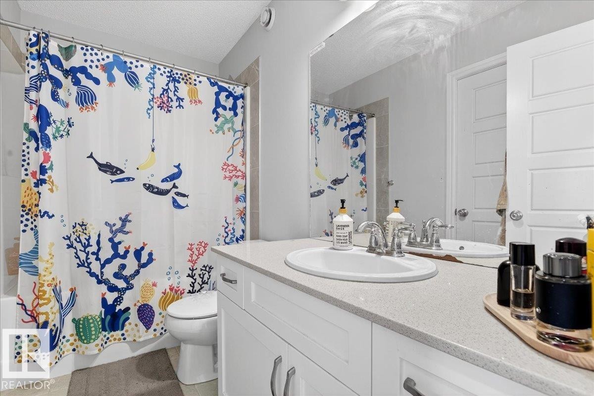 Bathroom featuring a white vanity with a light-colored countertop, an undermount sink, and a chrome faucet - 203 Cavanagh Common, Edmonton, AB - Indoor Photo Showing Bathroom