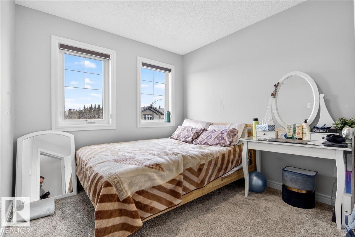 This room features two windows, light gray walls, and carpeted flooring - 203 Cavanagh Common, Edmonton, AB - Indoor Photo Showing Bedroom
